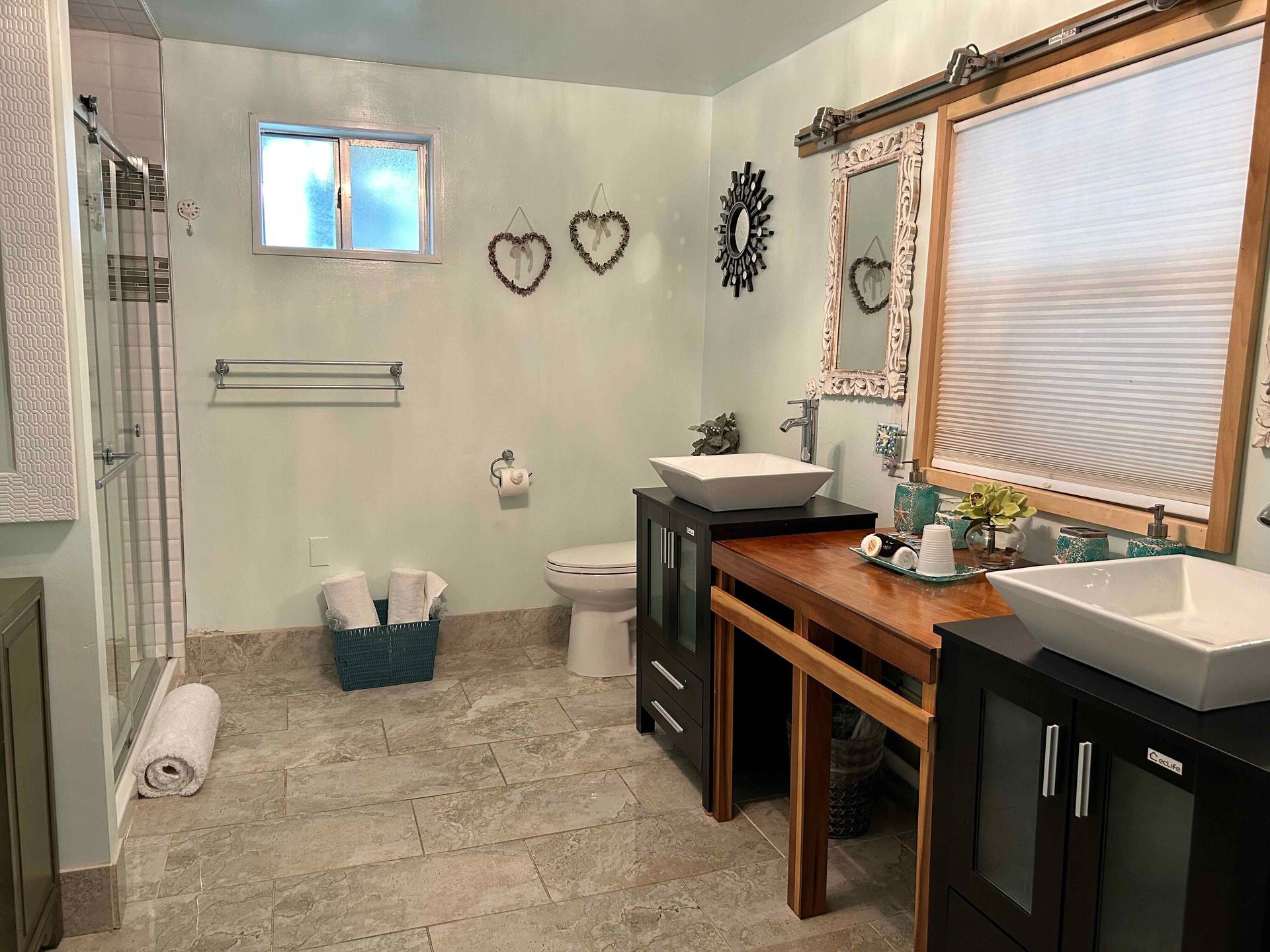 A bathroom with two sinks , a toilet , and a window.