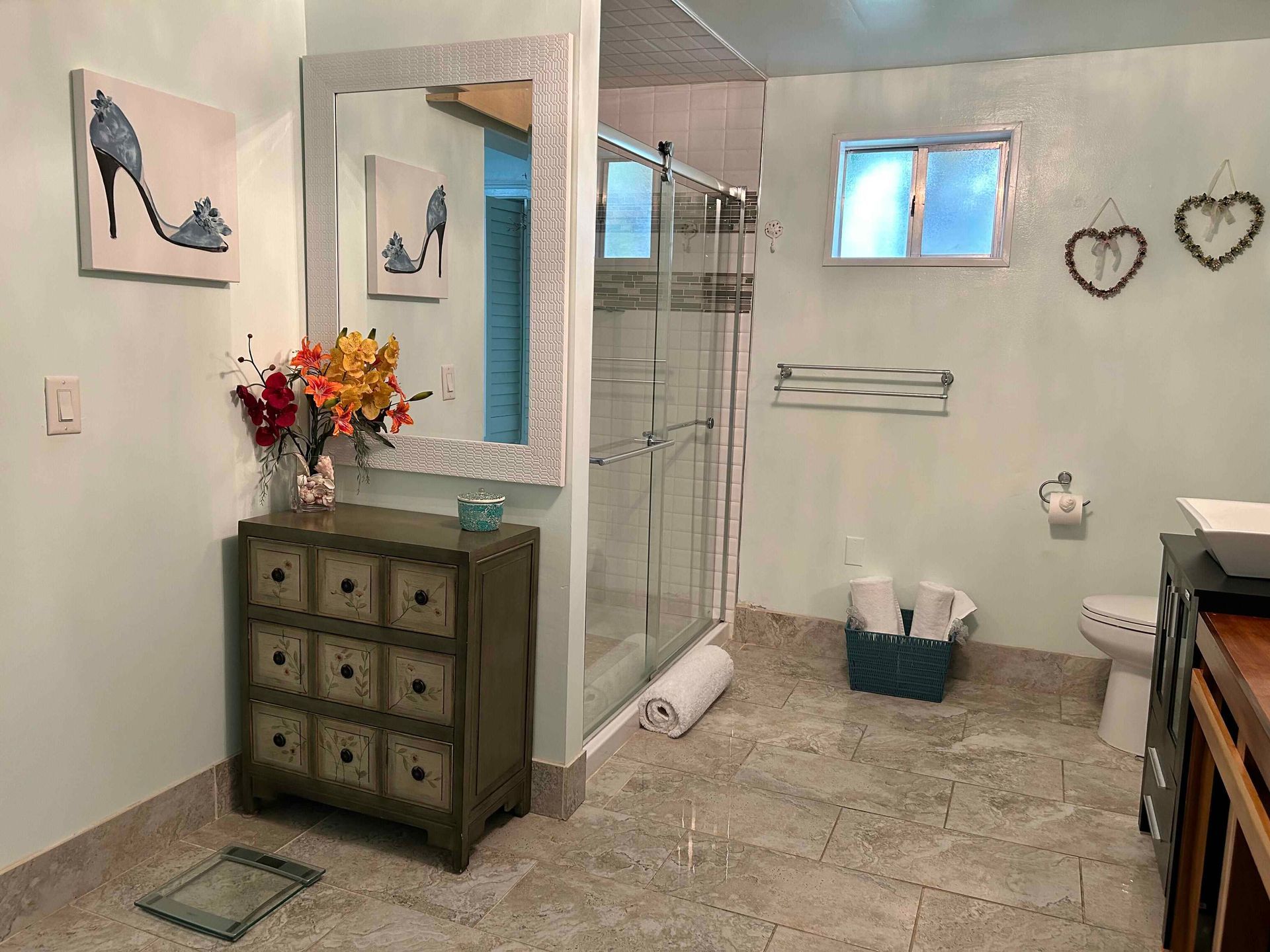 A bathroom with a toilet , sink , mirror and walk in shower.