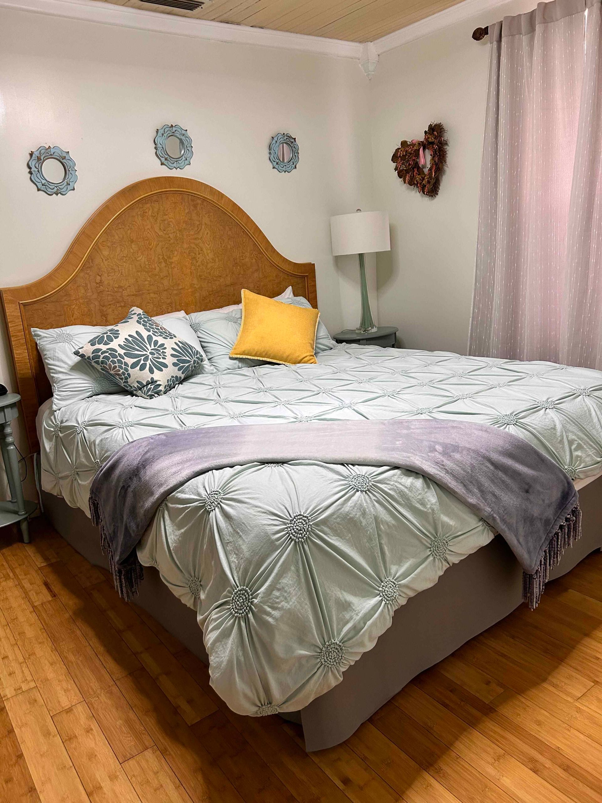 A bedroom with a bed , nightstand , lamp and window.