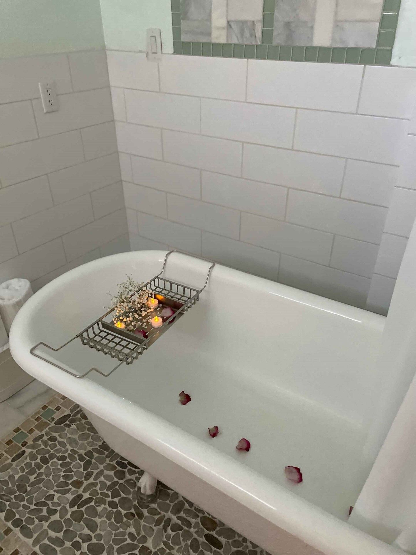 A bathtub with petals floating in it in a bathroom.