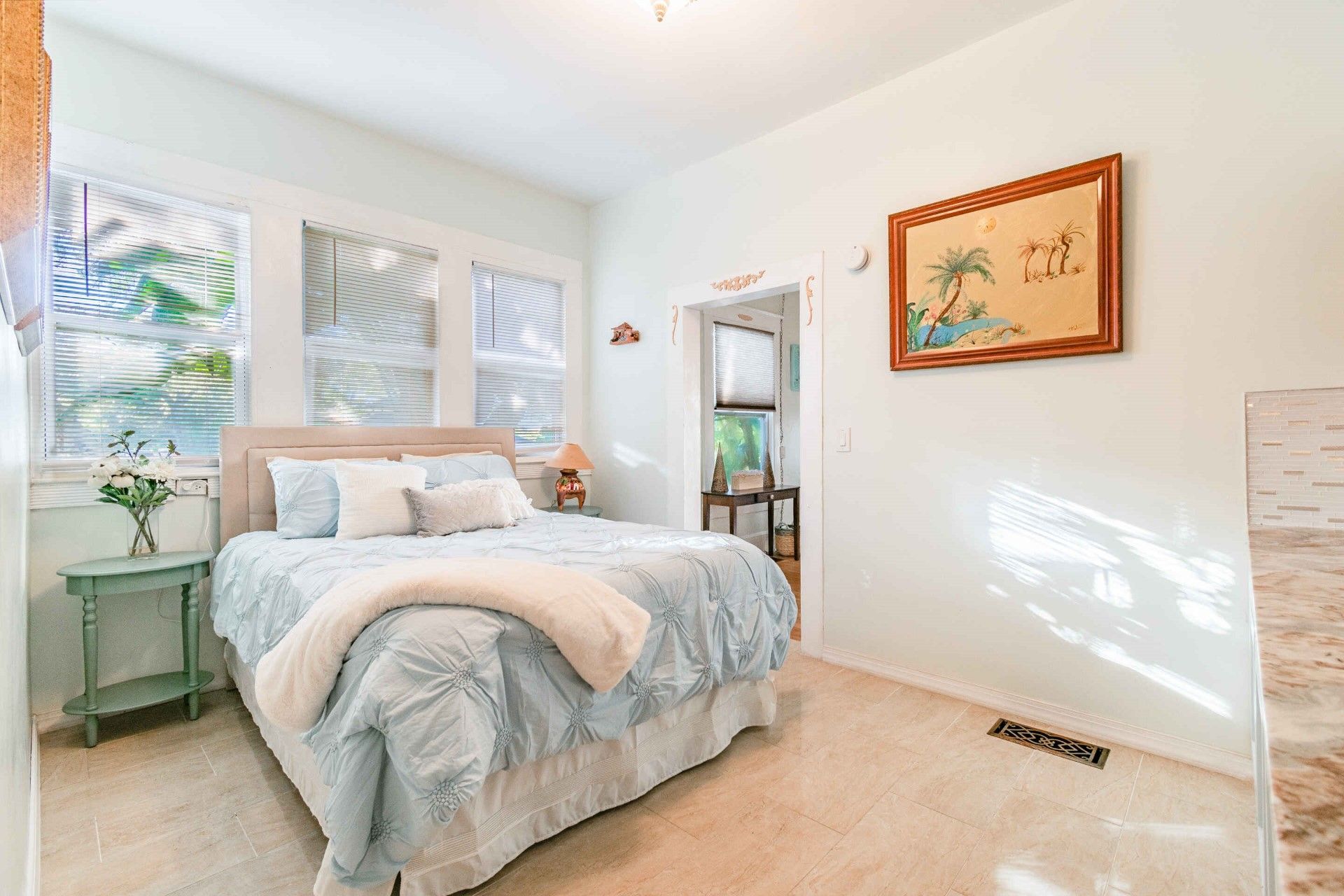A bedroom with a bed , nightstand , and a picture on the wall.