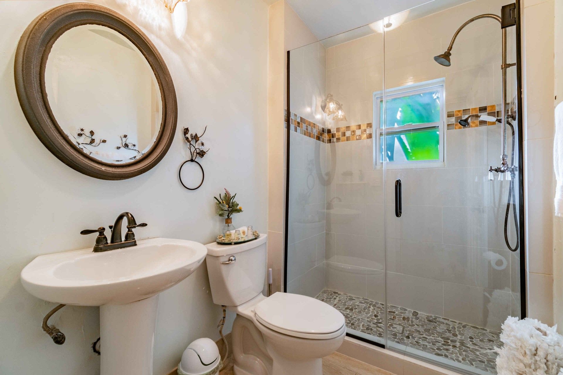 A bathroom with a toilet , sink , mirror and shower.