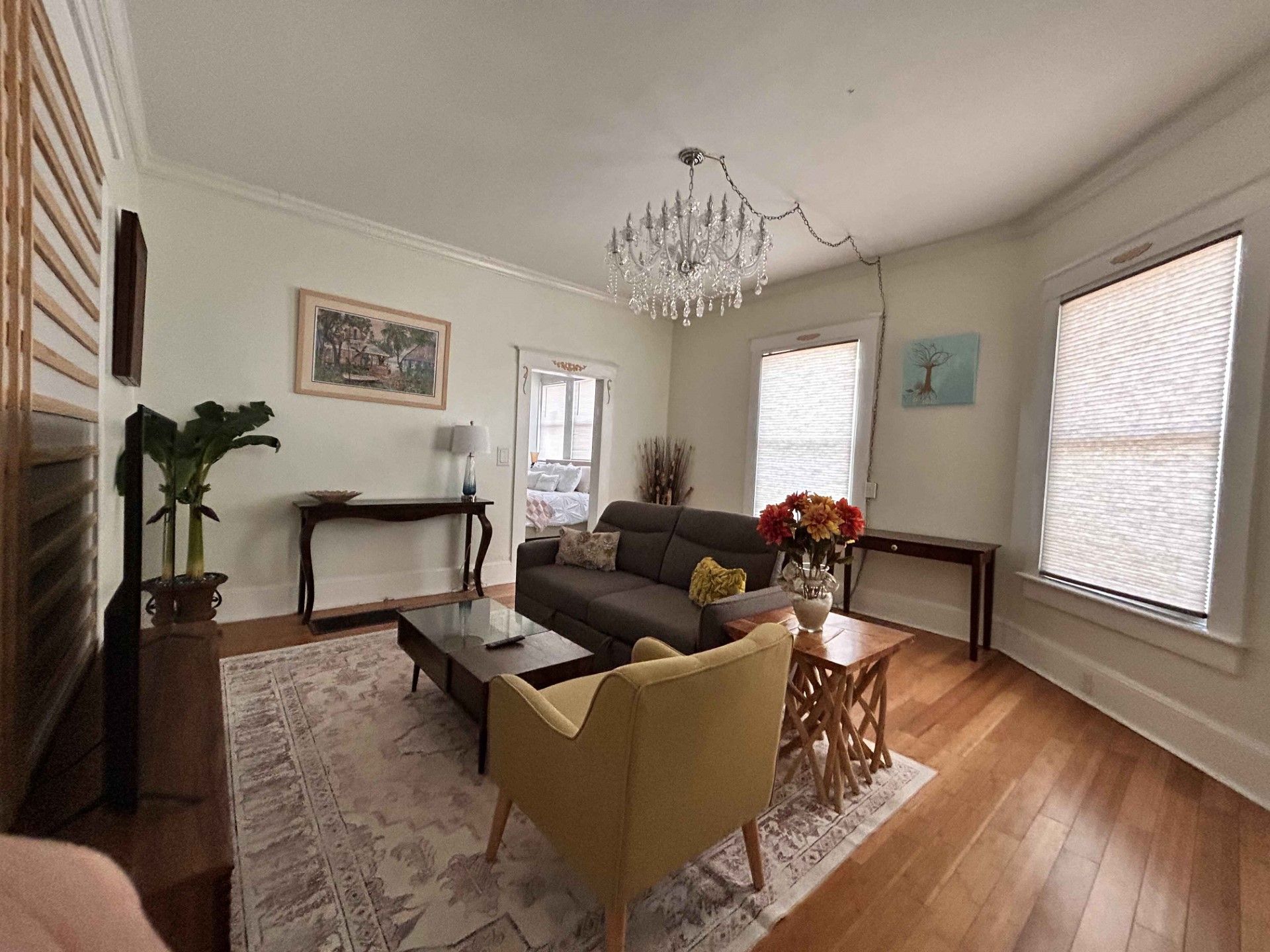 A living room with a couch , chairs , coffee table and chandelier.
