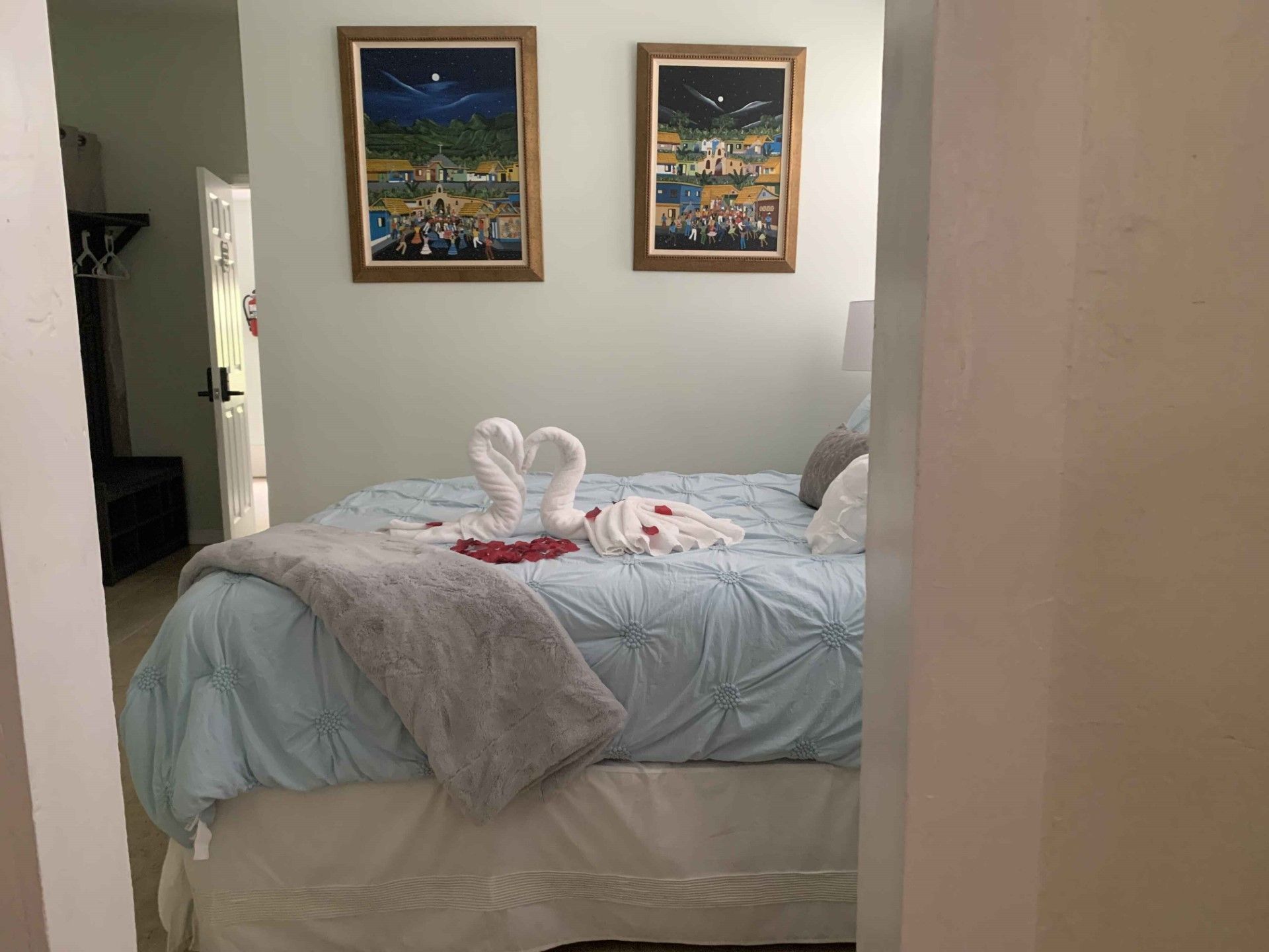 A bedroom with a bed and two paintings on the wall.