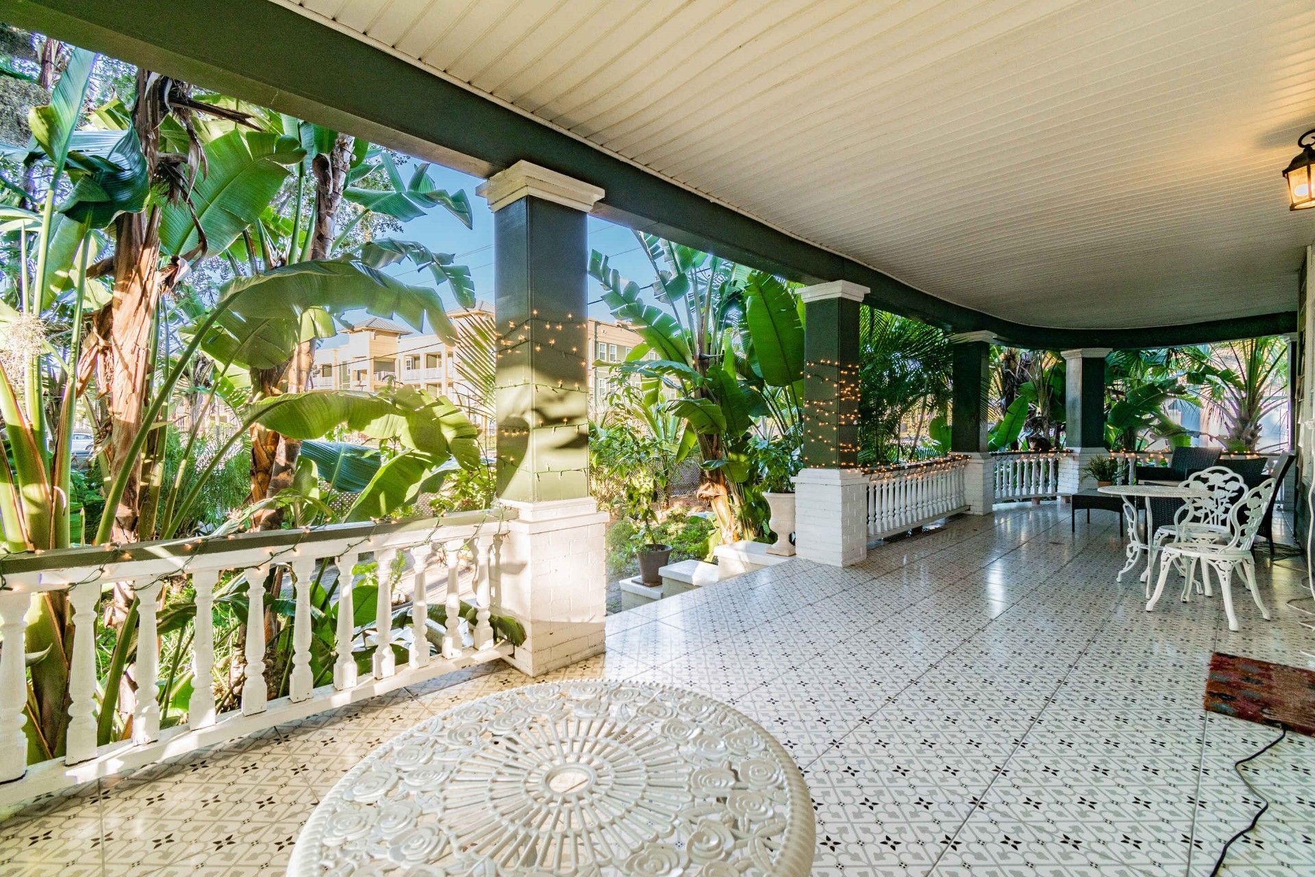 There is a large porch with a table and chairs on it.