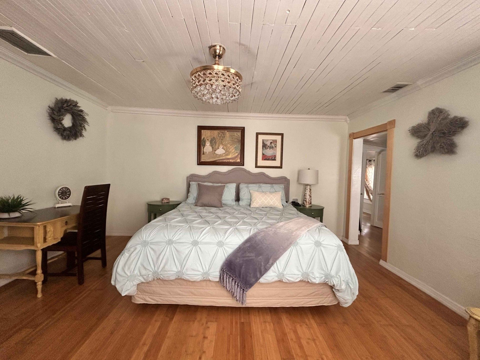 A bedroom with a bed , desk , chair and ceiling fan.