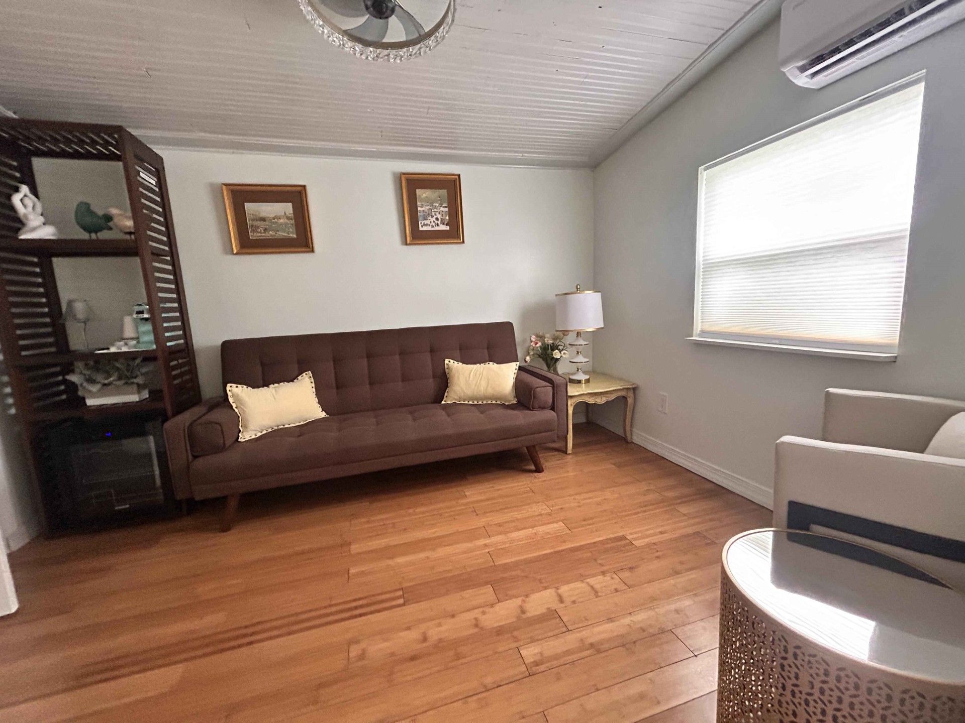 A living room with a couch , chair , table and window.