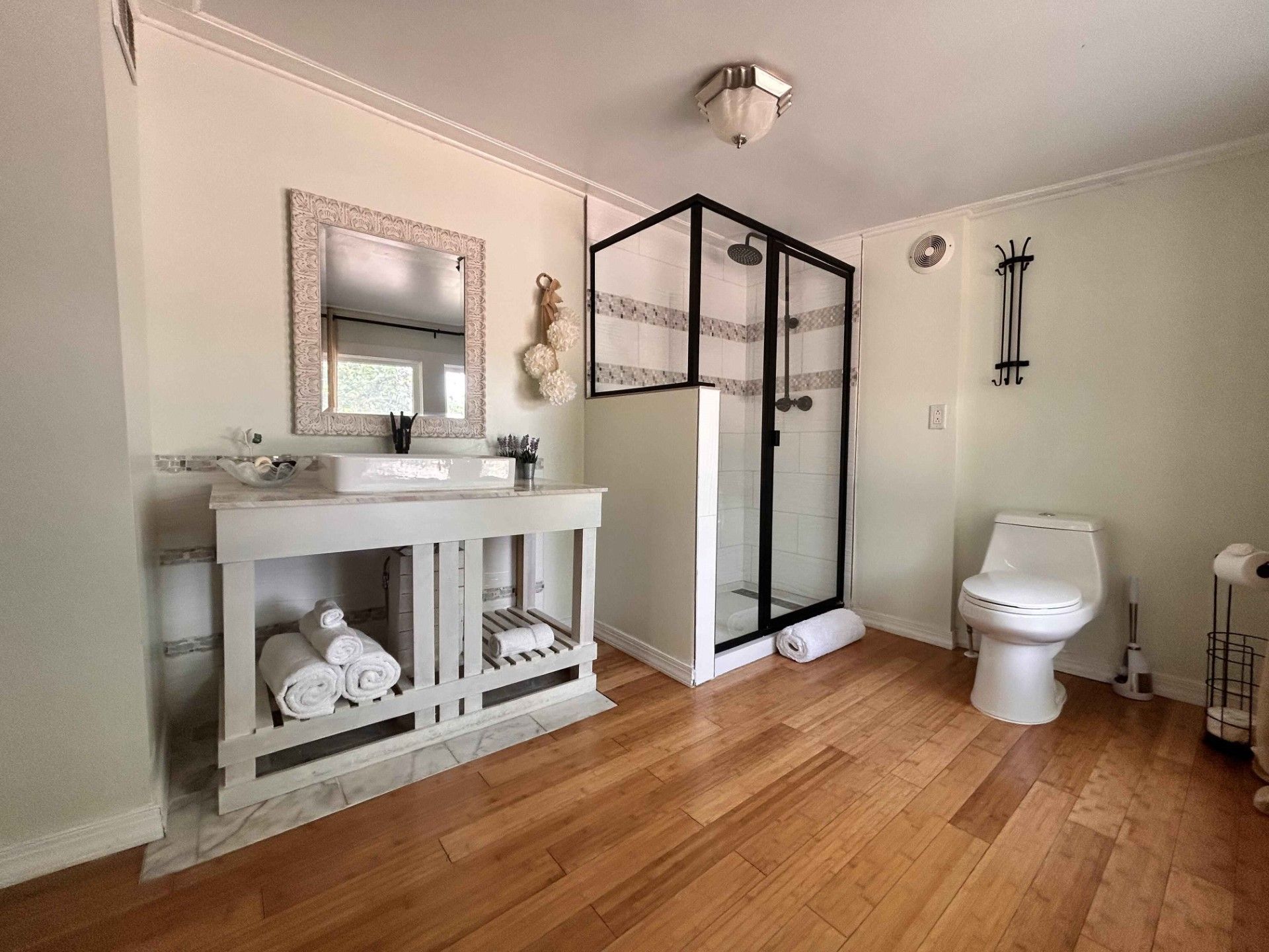 A bathroom with a toilet , sink , mirror and shower.