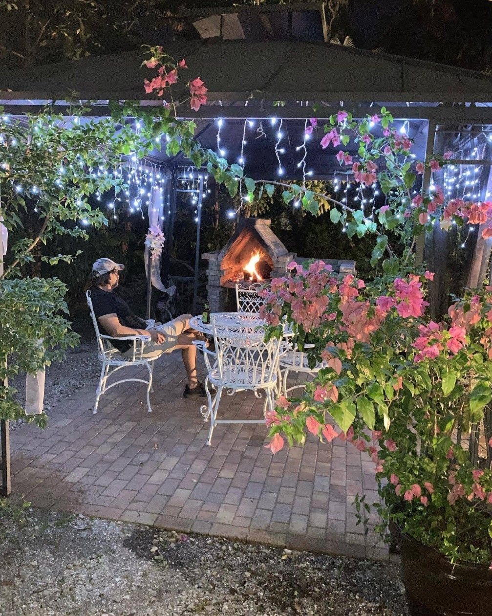 A man is sitting in a chair under a gazebo with a fireplace.
