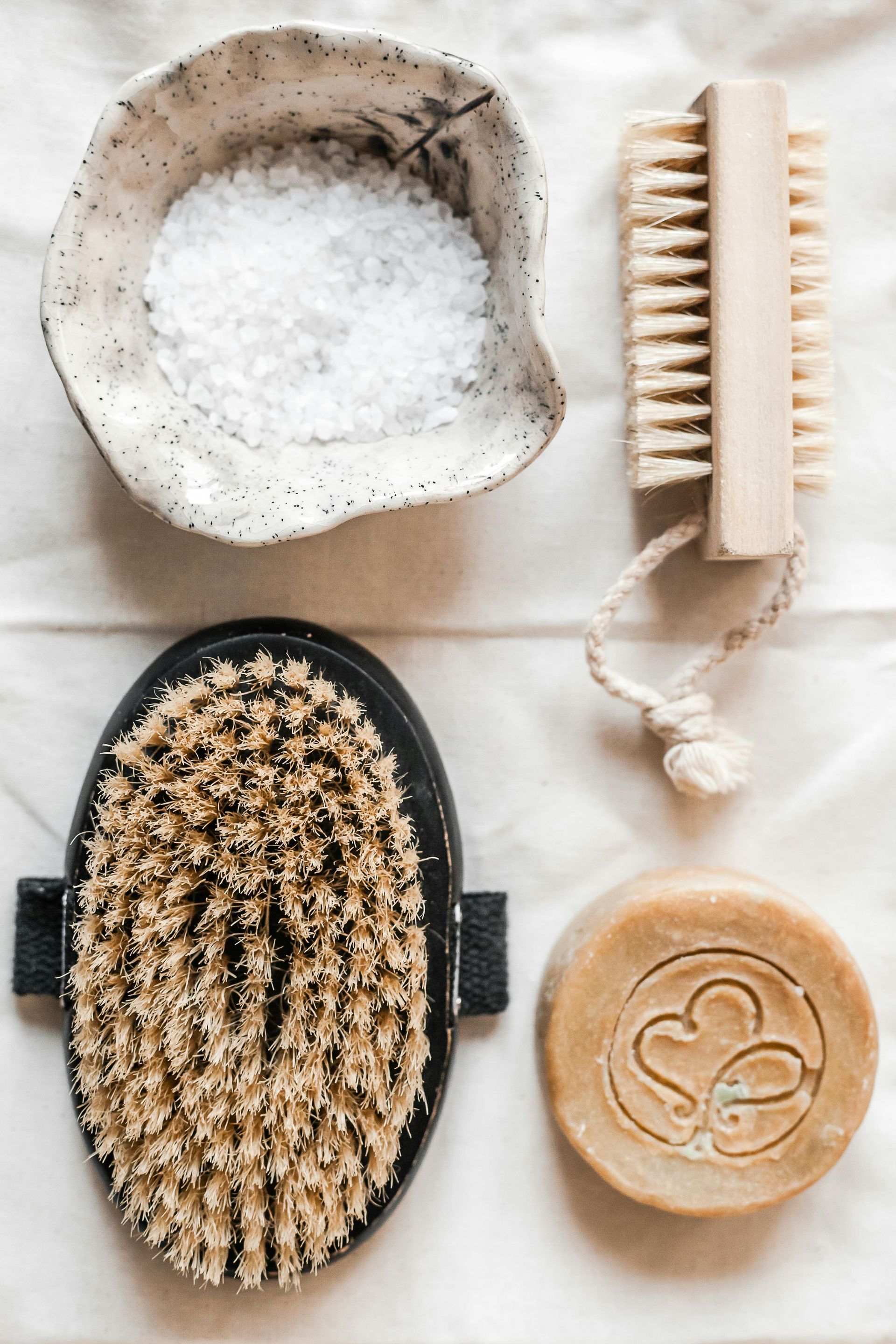 There is a bowl of salt , a brush , and a soap on the table.