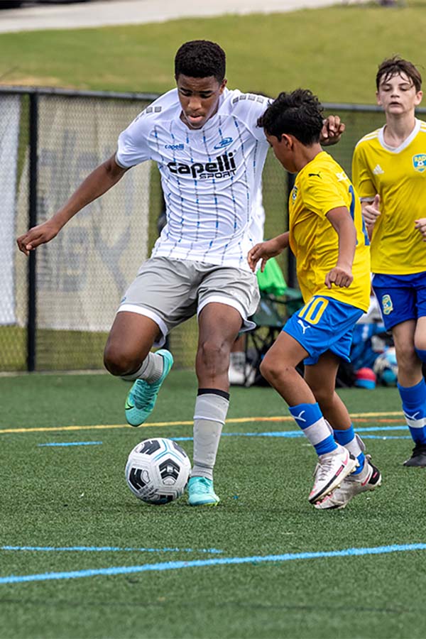 Two soccer players are playing a game of soccer on a field.
