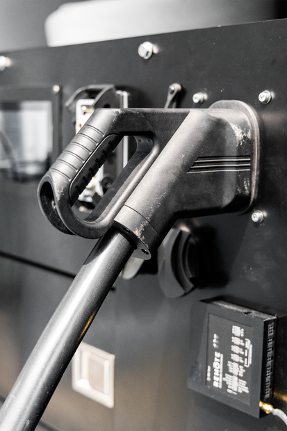 Close-up of a black cable plugged into a device port on a panel, with a handhold nearby.