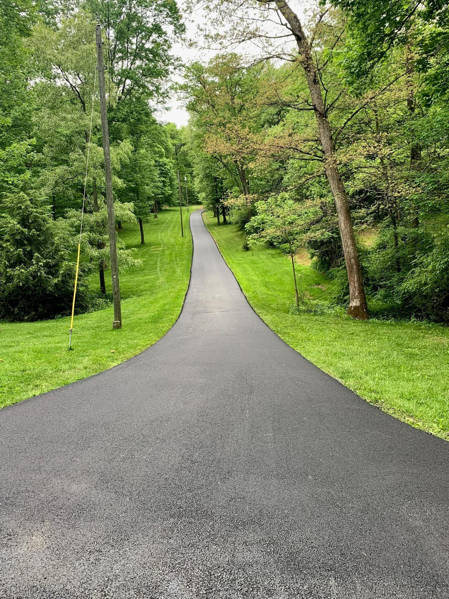 A road going through a park surrounded by trees and grass.