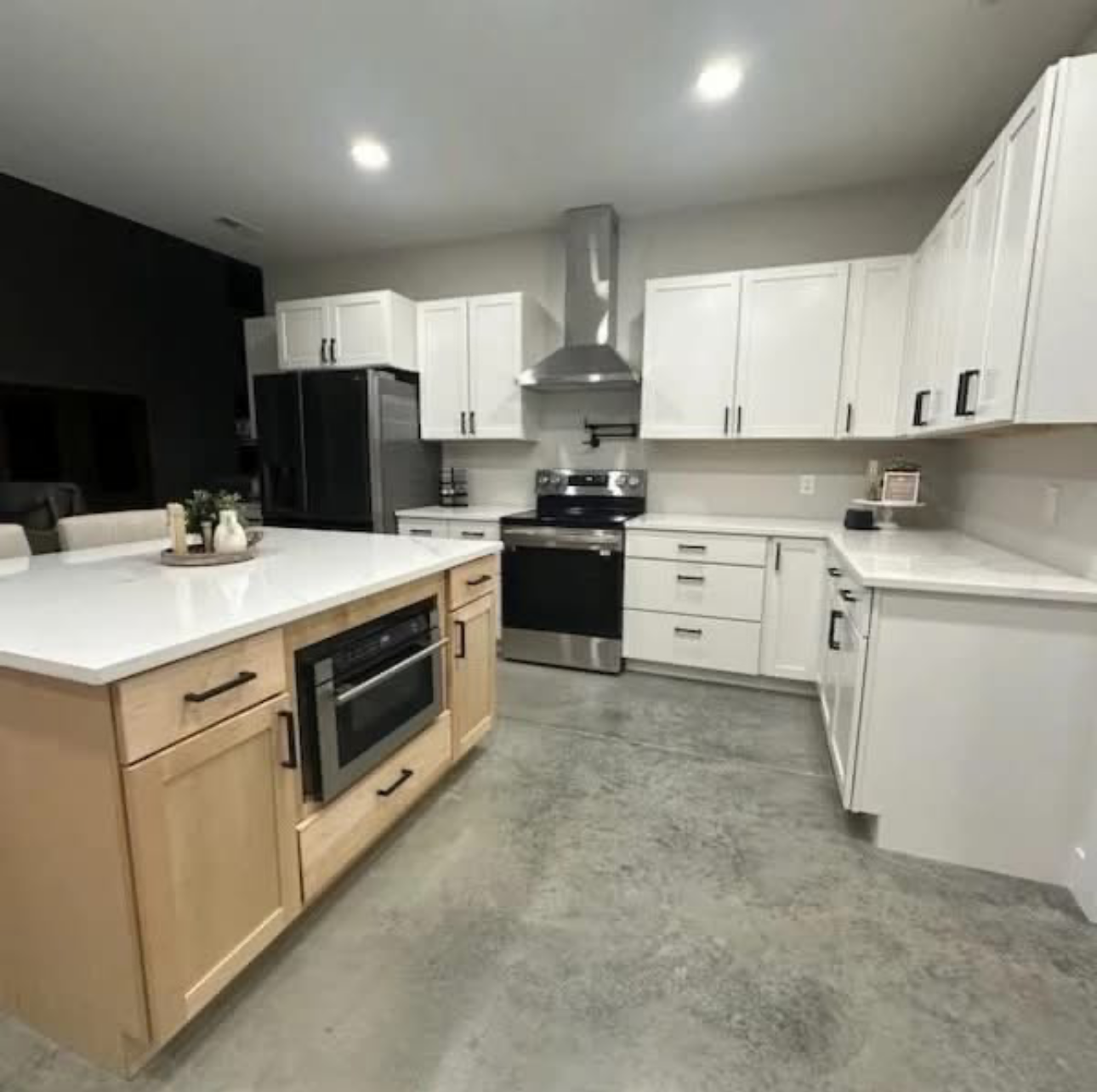 Modern kitchen with white cabinets, island with microwave, and stainless steel appliances.