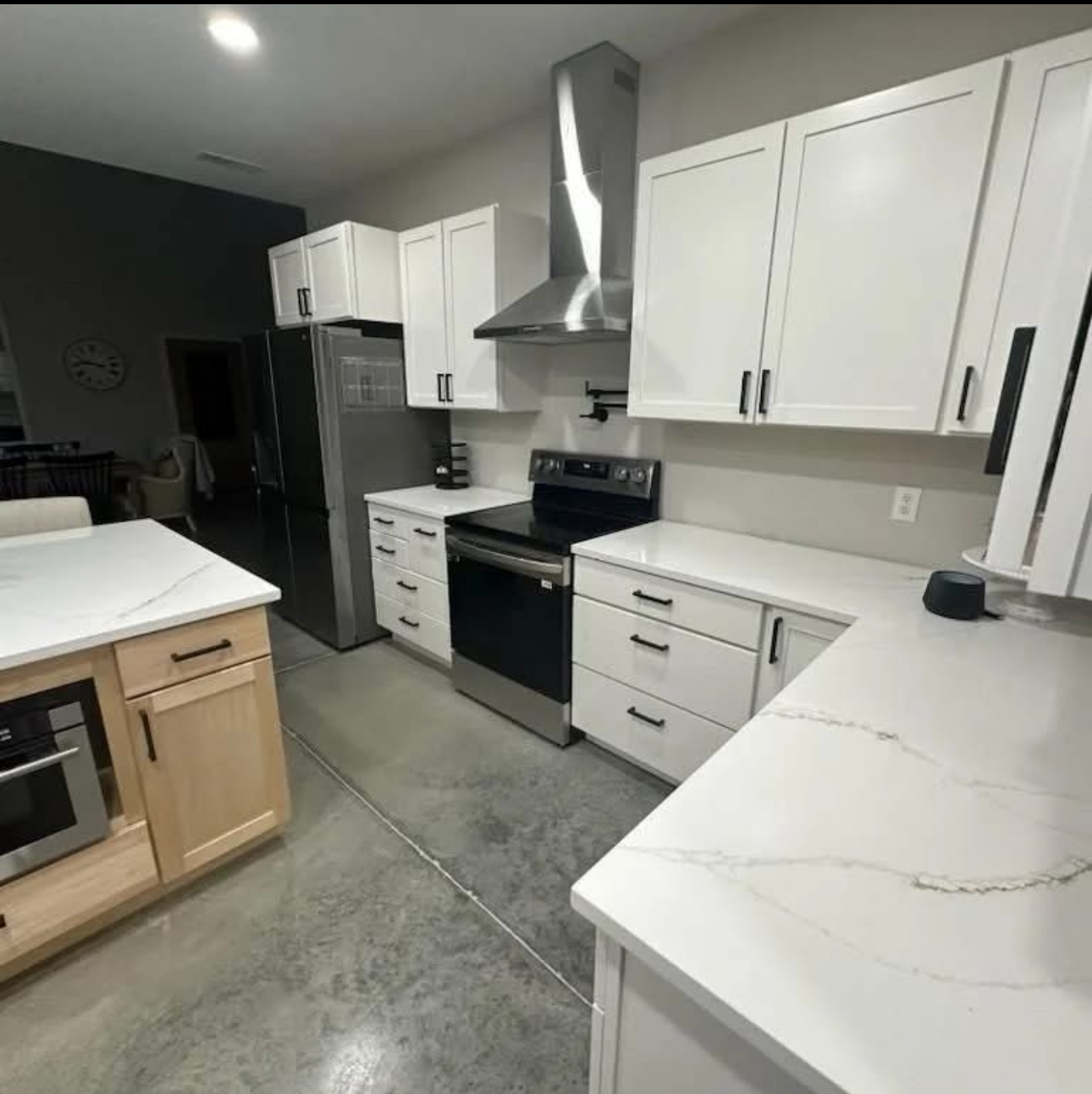 Modern kitchen with white cabinets, stainless steel appliances, and light countertops.