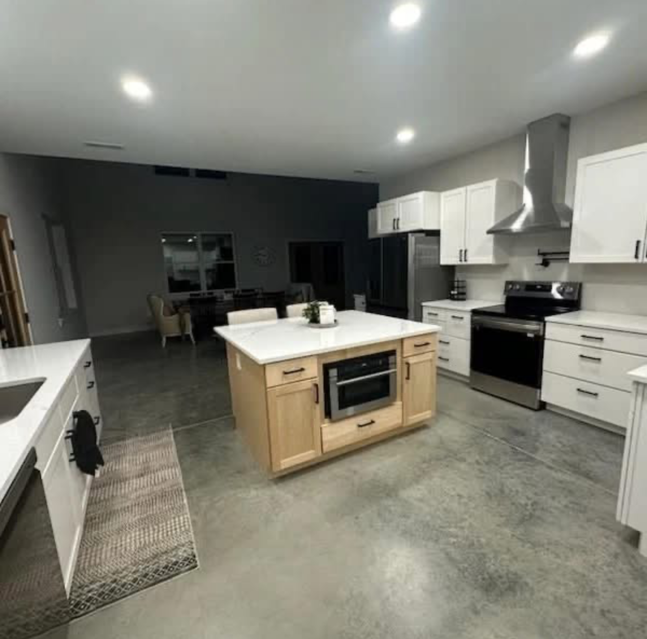 Modern kitchen with white cabinets, wood island, stainless steel appliances, and concrete floor.