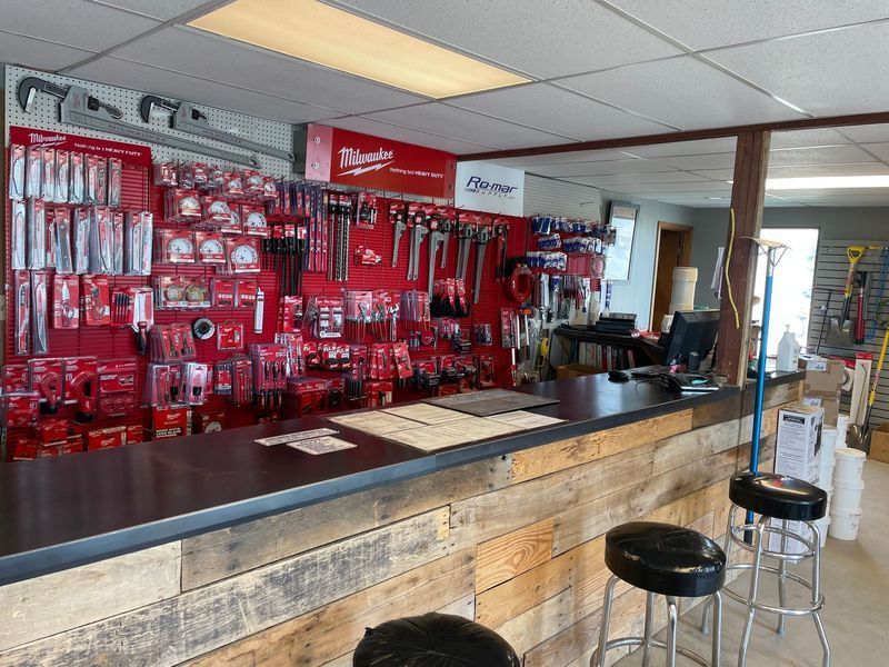 Tool store interior, red tools on display, counter with stools, Milwaukee sign visible.