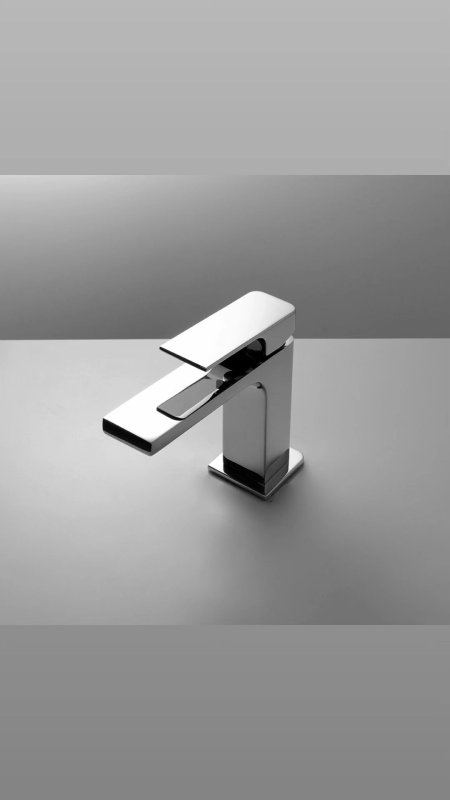 Il rubinetto del lavandino del bagno è appoggiato su un tavolo bianco.
