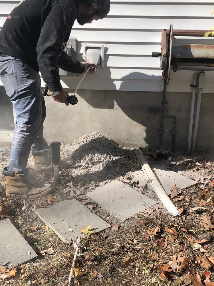 Person using a power tool to work on the exterior wall of a building.
