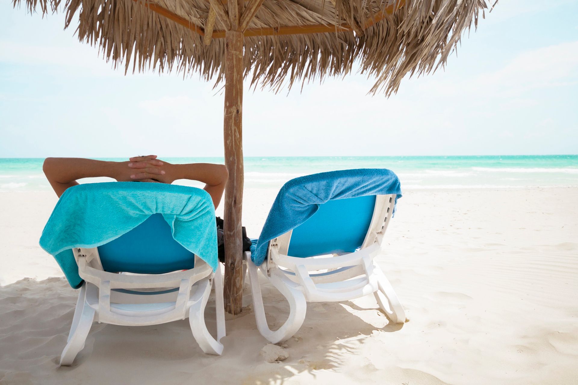 A person is sitting under an umbrella on the beach