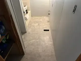 A hallway leading to a bathroom with a tiled floor.