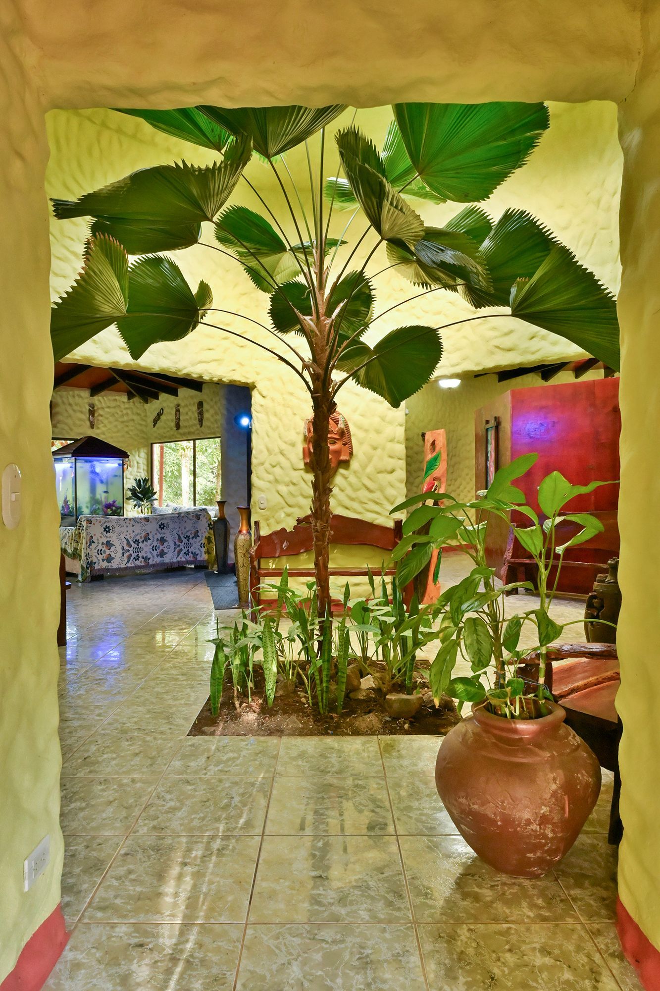 View through an arched doorway of a hallway with a potted plant and a tree-like art installation.