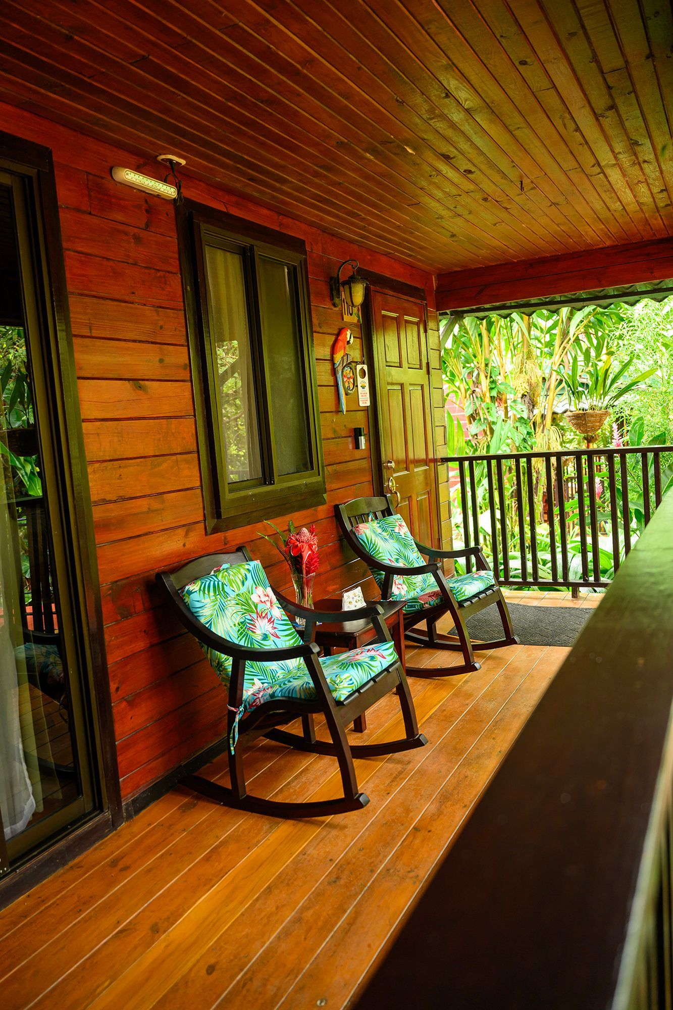 Wooden porch with two rocking chairs, small table, and open door.