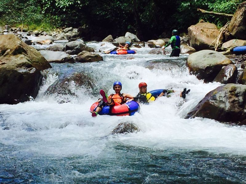 People in inner tubes navigating a whitewater river.