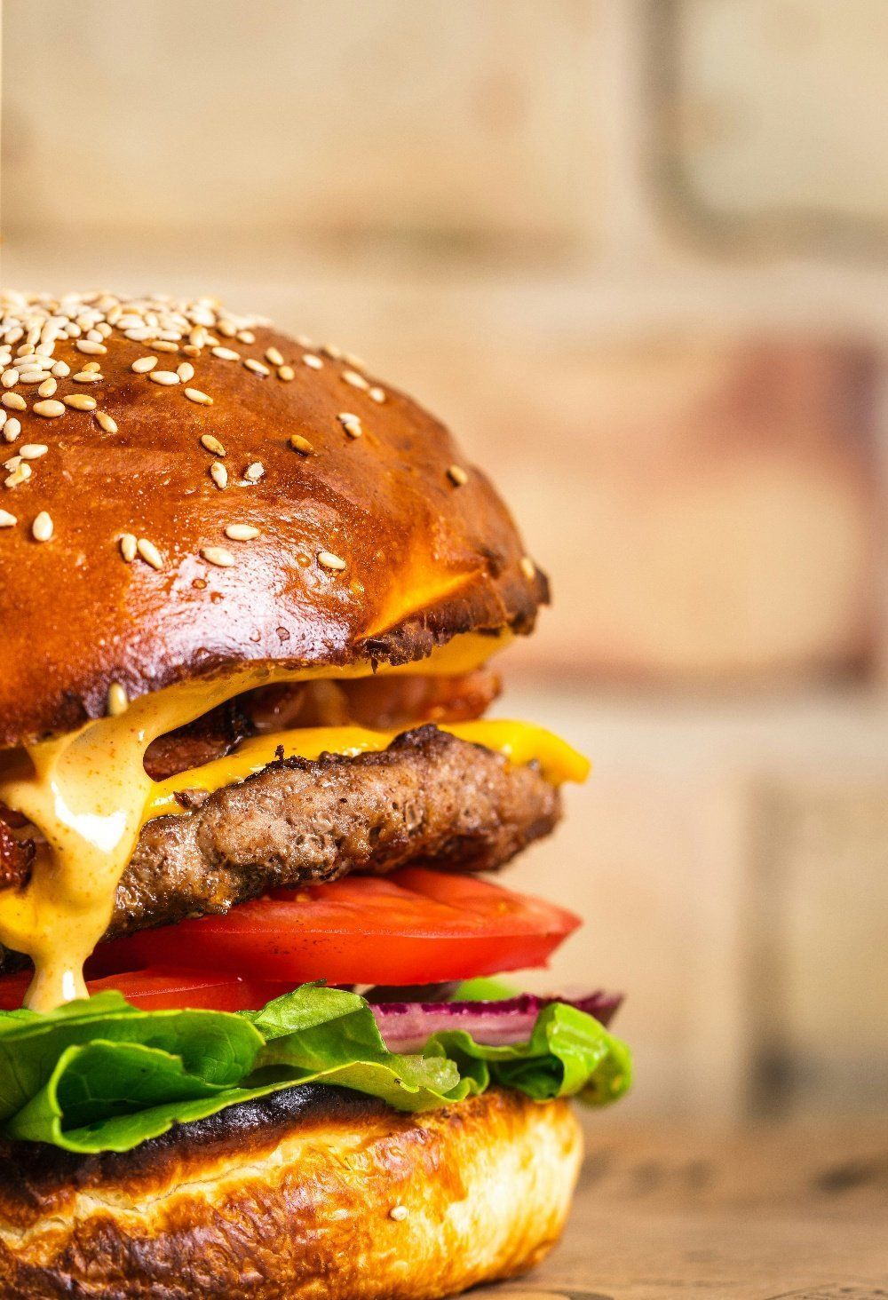 Cheeseburger with melted cheese, tomato, and lettuce on a sesame seed bun.