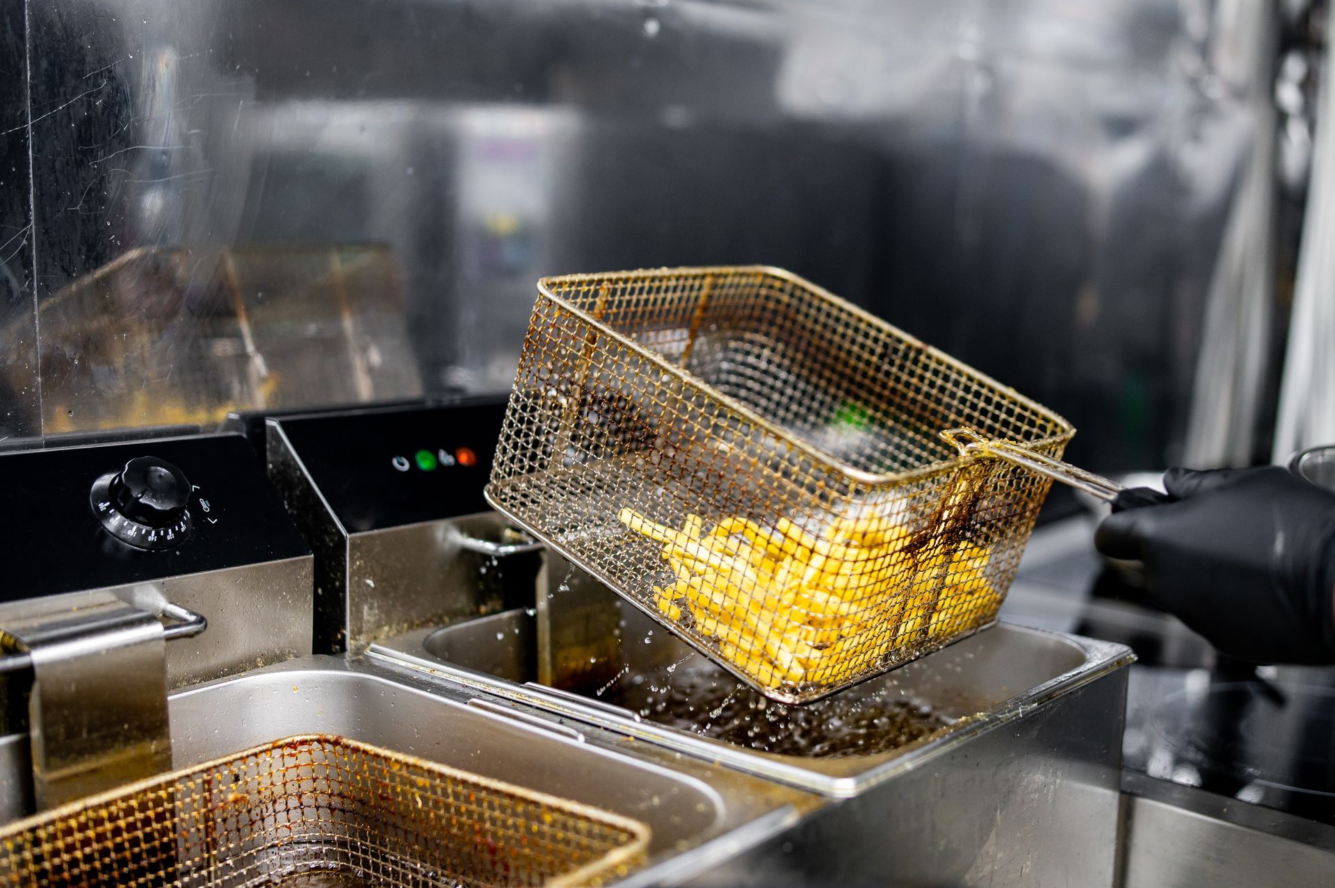 Employee frying food in oil that will be collected by a commercial kitchen and restaurant grease trap