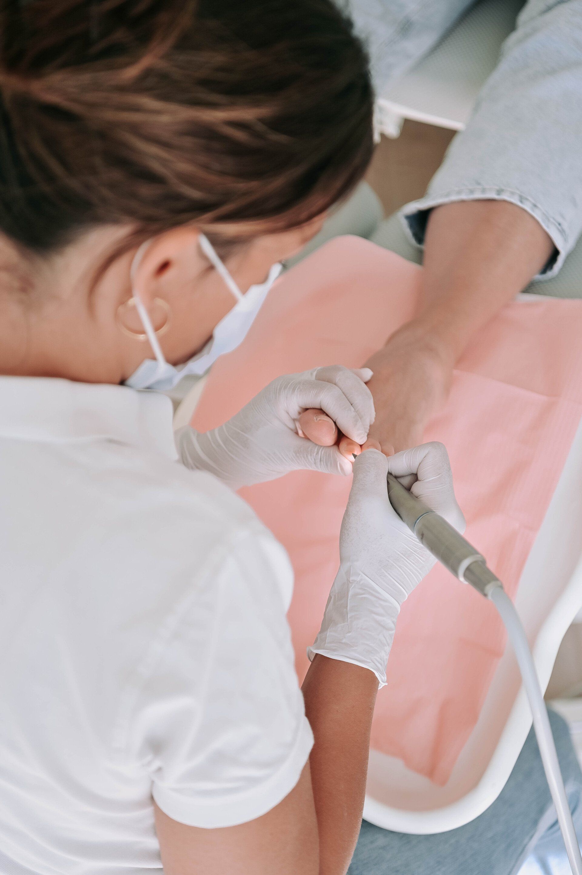 Een persoon in een medische omgeving krijgt voetverzorging van een professional die handschoenen draagt.
