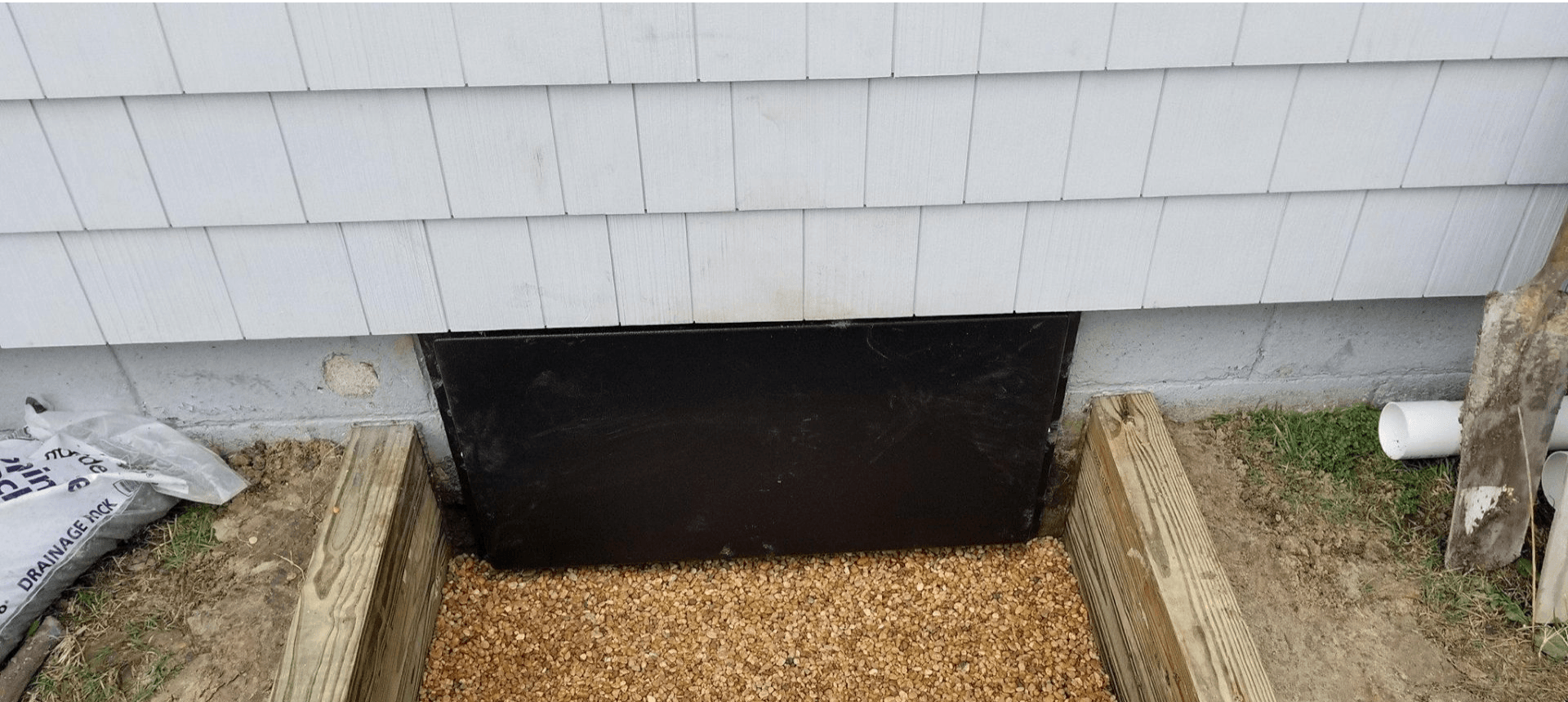 There is a window in the foundation of a house.