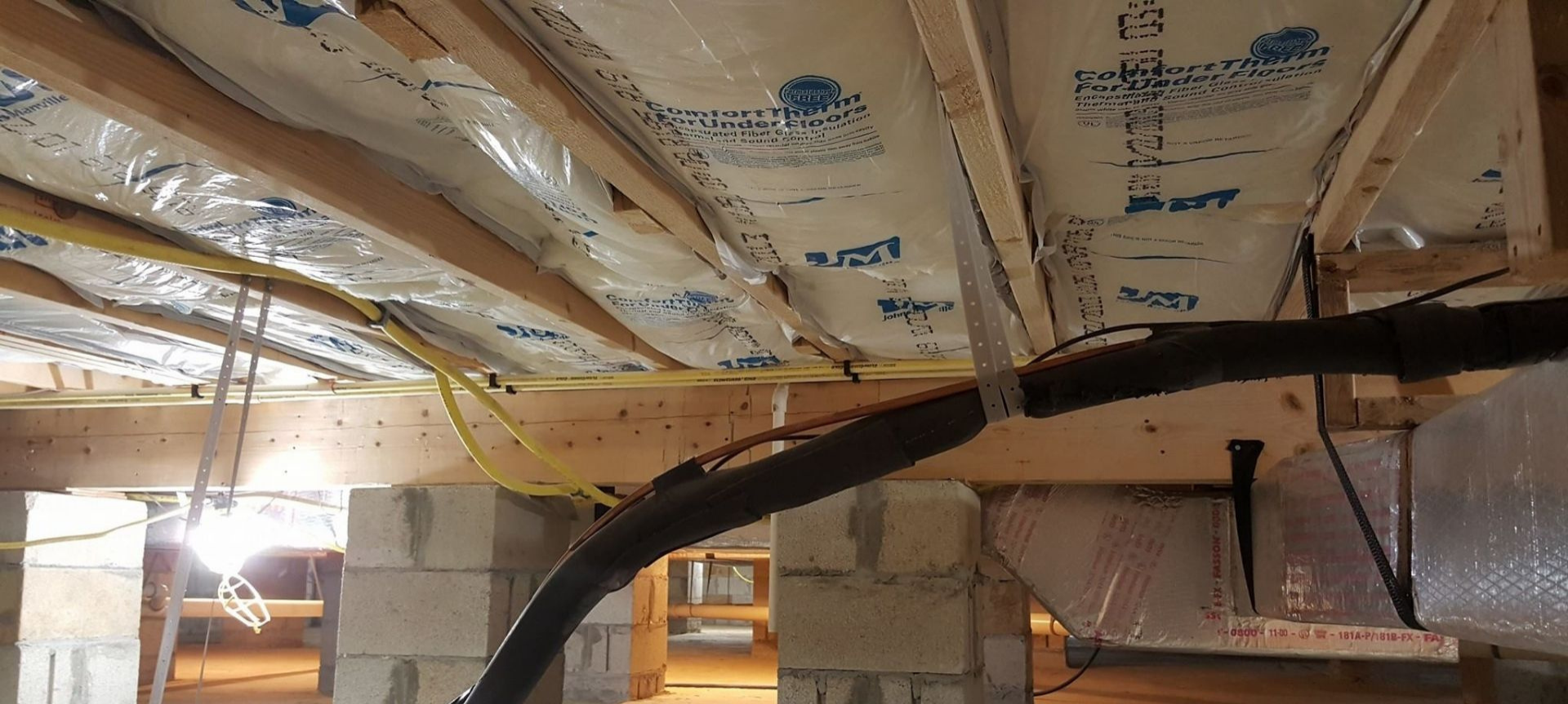 Insulated basement ceiling with exposed joists, wiring, and a black pipe crossing overhead