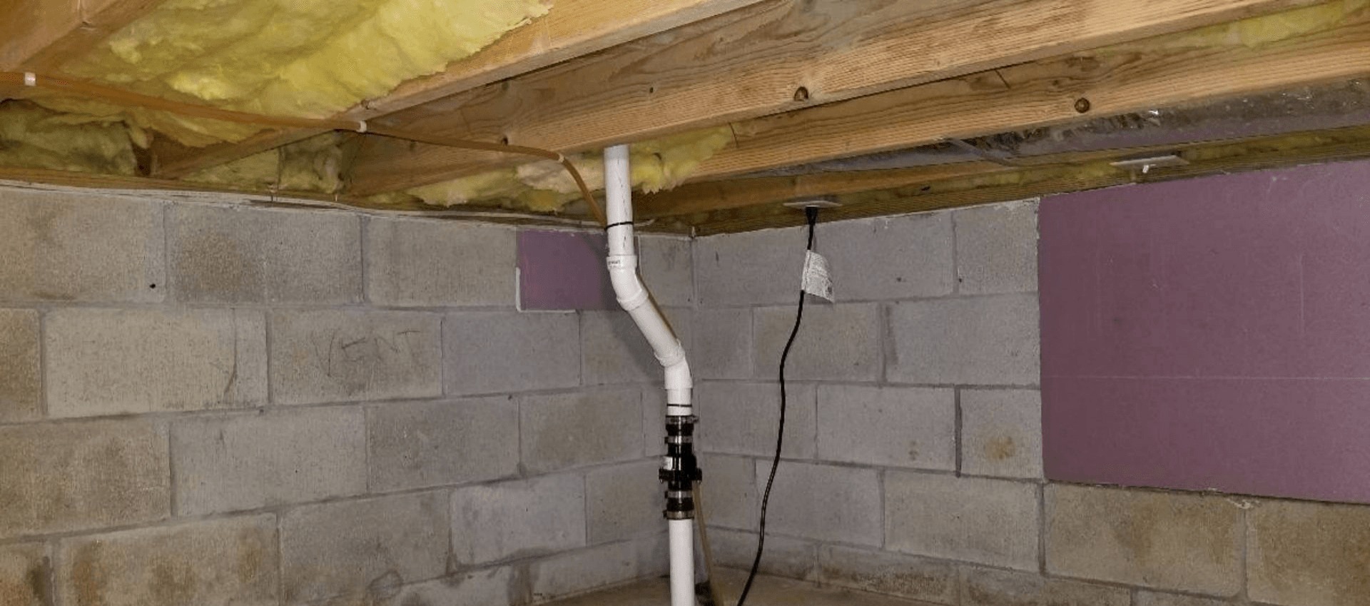 A basement with a pipe coming out of the ceiling.
