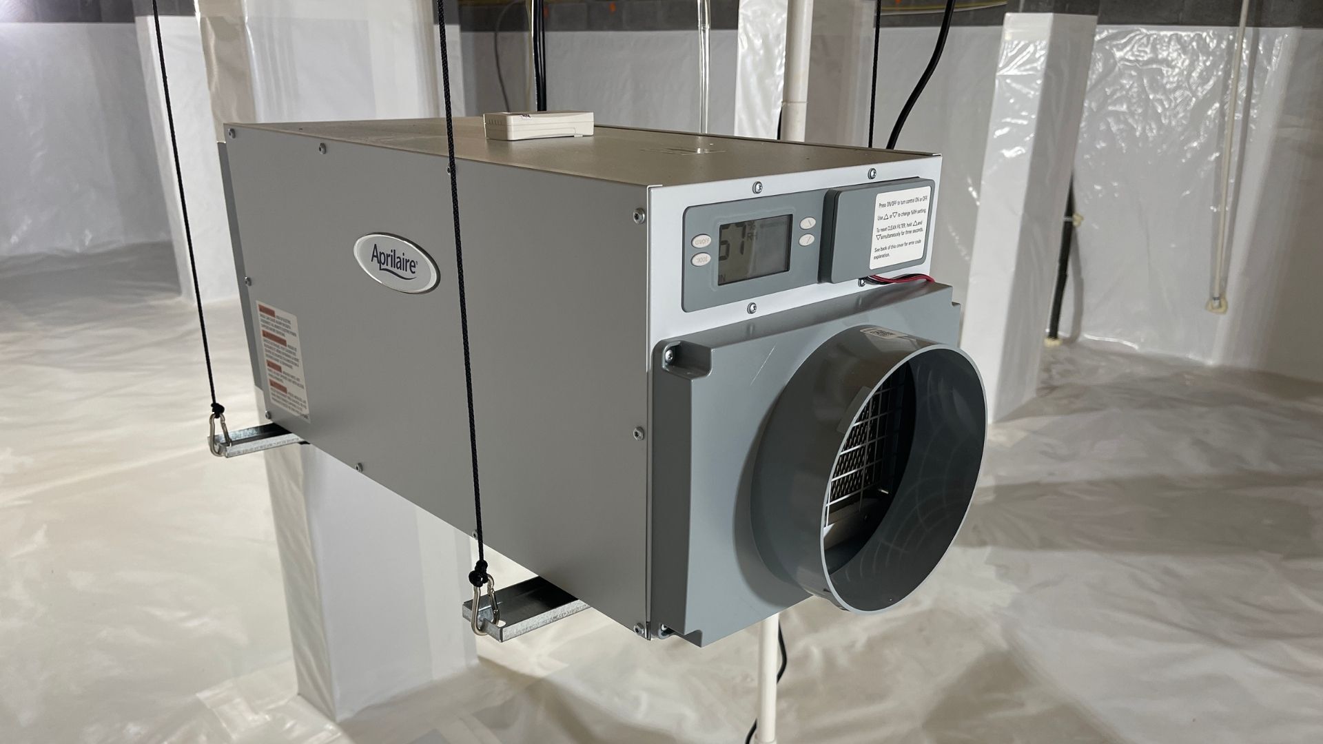 Gray industrial HVAC unit with a large circular duct opening and control panel on a plastic-covered floor