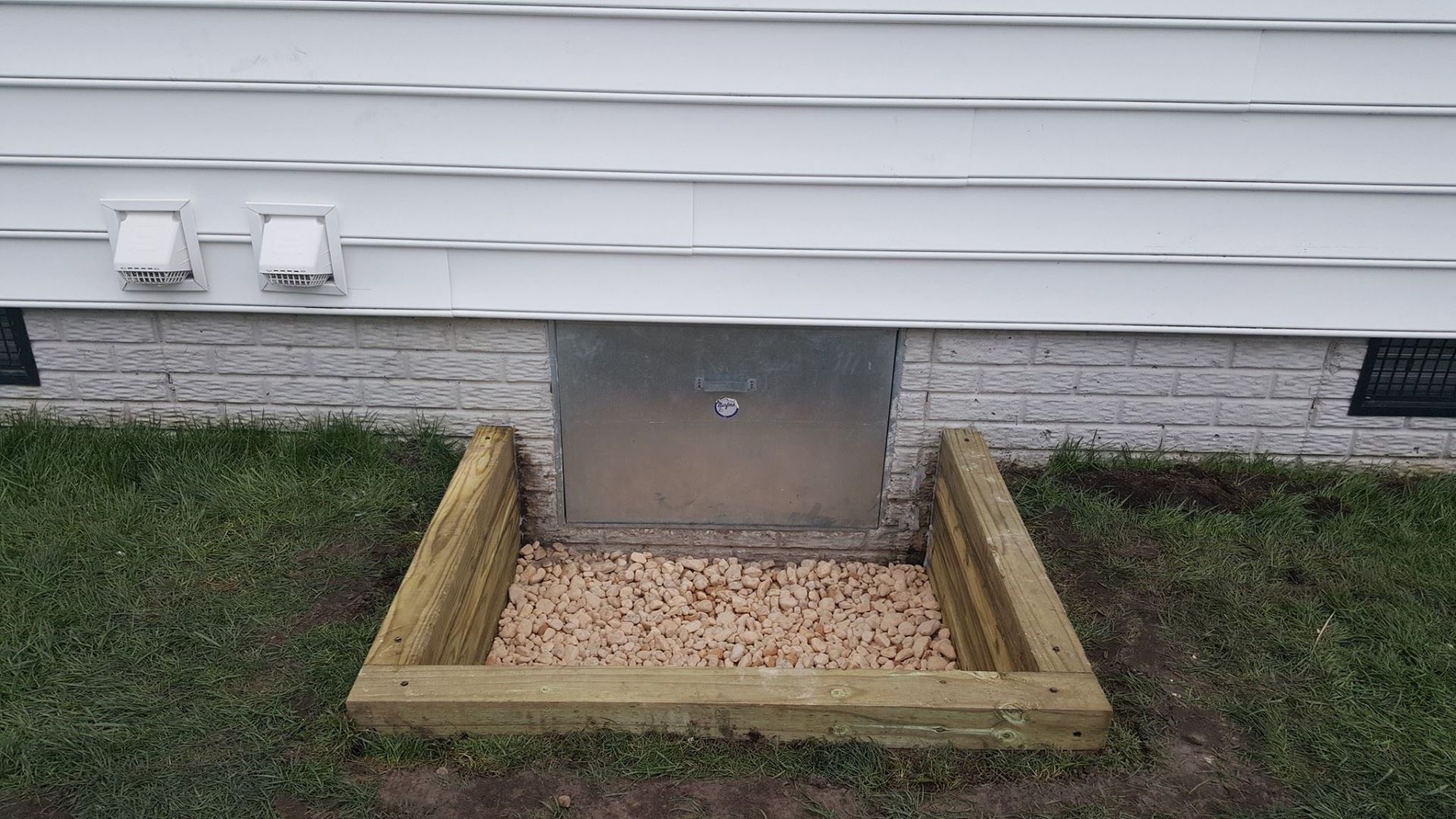 A wooden box is sitting under a window in the basement of a house.