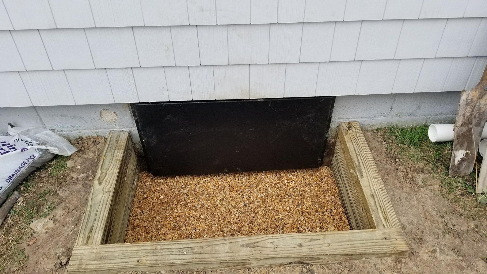 A window well is being built into the side of a house.