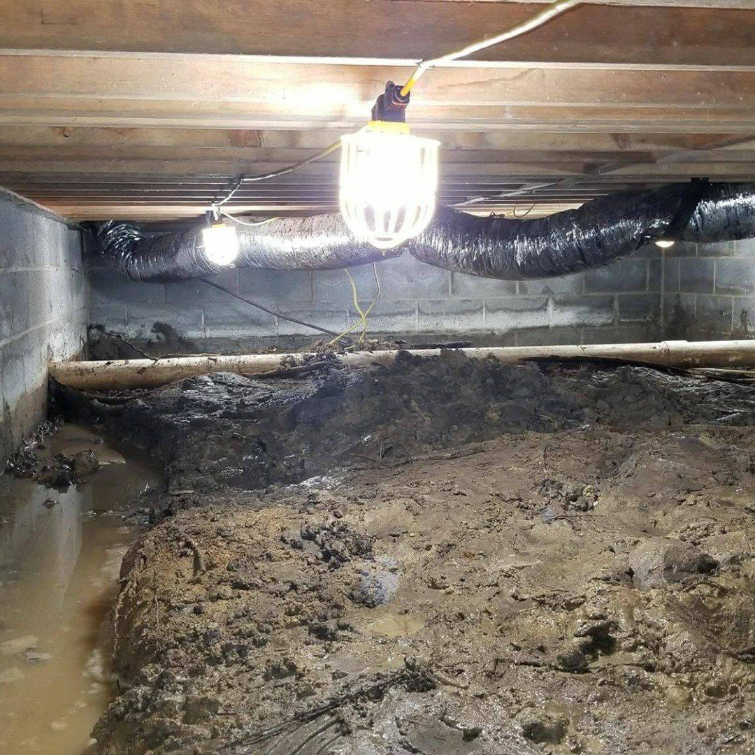 A muddy basement with a light hanging from the ceiling.
