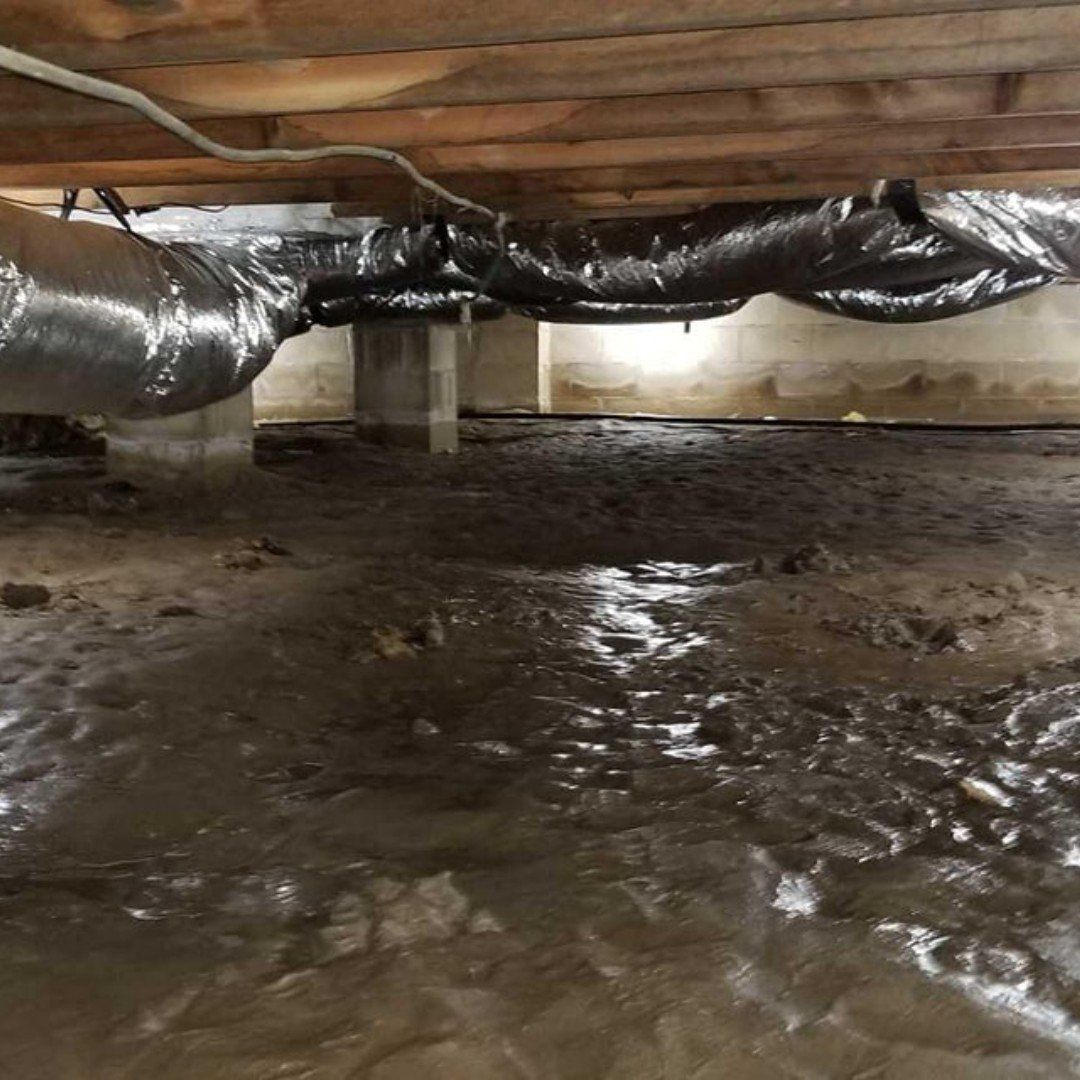 A muddy basement with a lot of pipes coming out of it