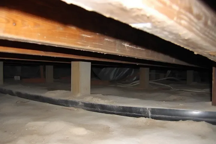 Under-bed storage space with a black cable and wooden slats visible