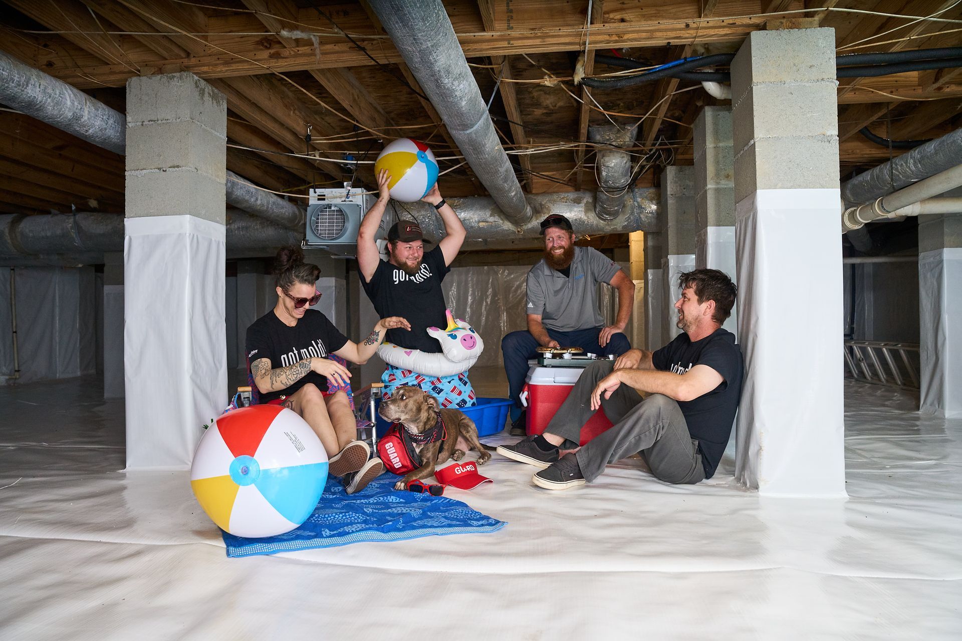 Lowcountry Crawlspaces crew relaxing on a finished crawl space encapsulation with beach balls and a cooler