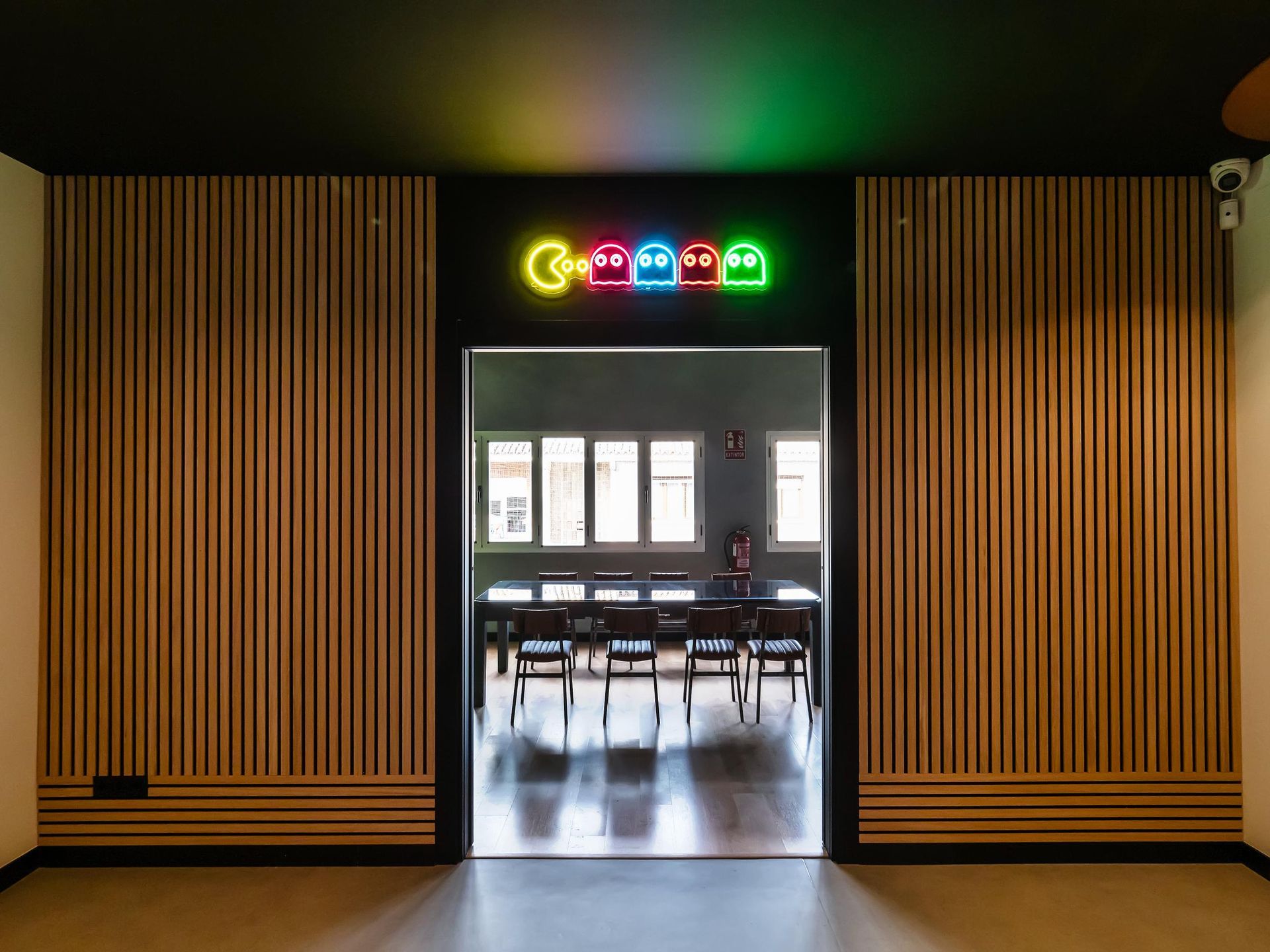 A room with a wooden wall and a neon sign on the wall.