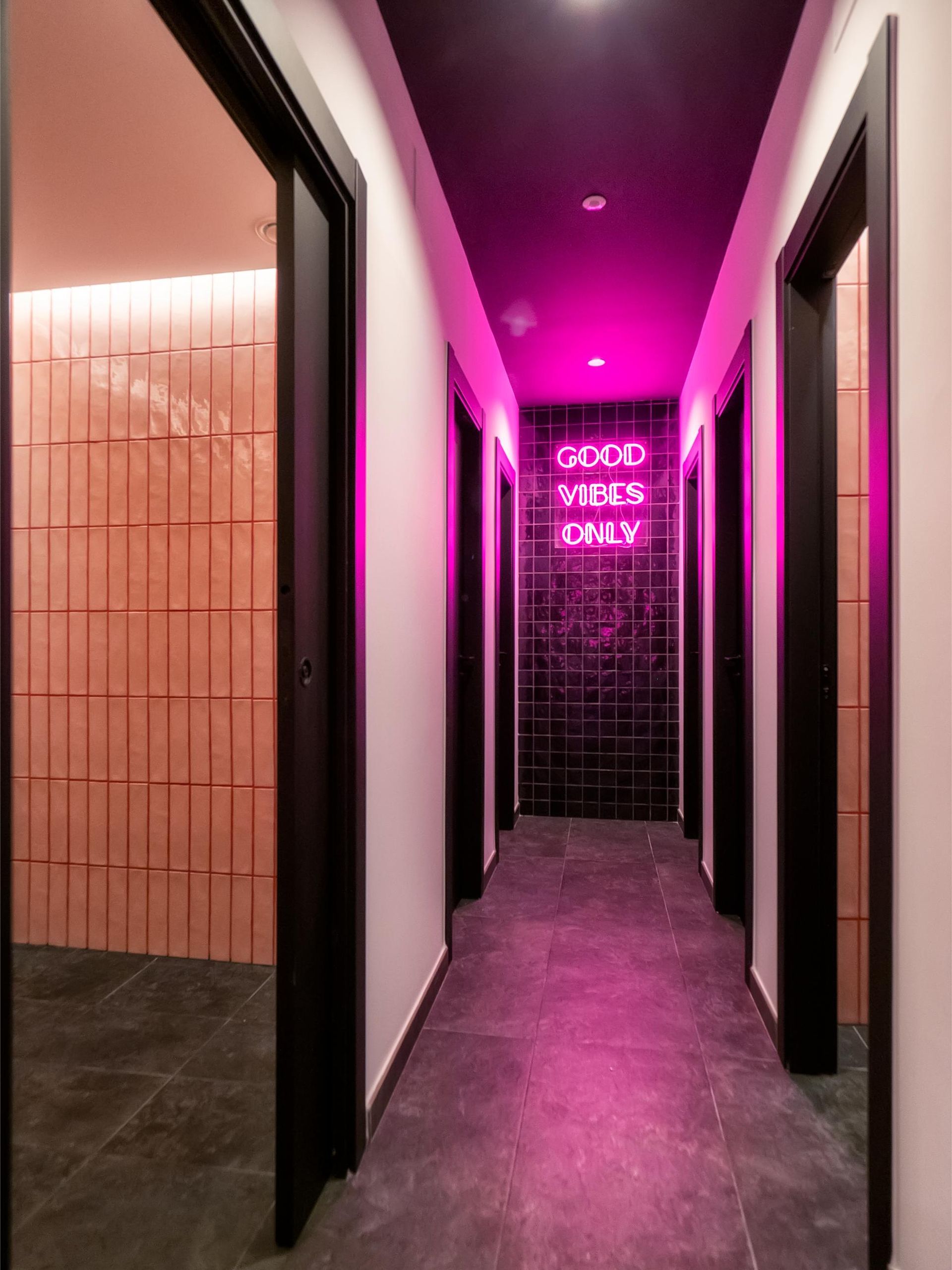 A long hallway with a neon sign that says `` good vibes daily ''.