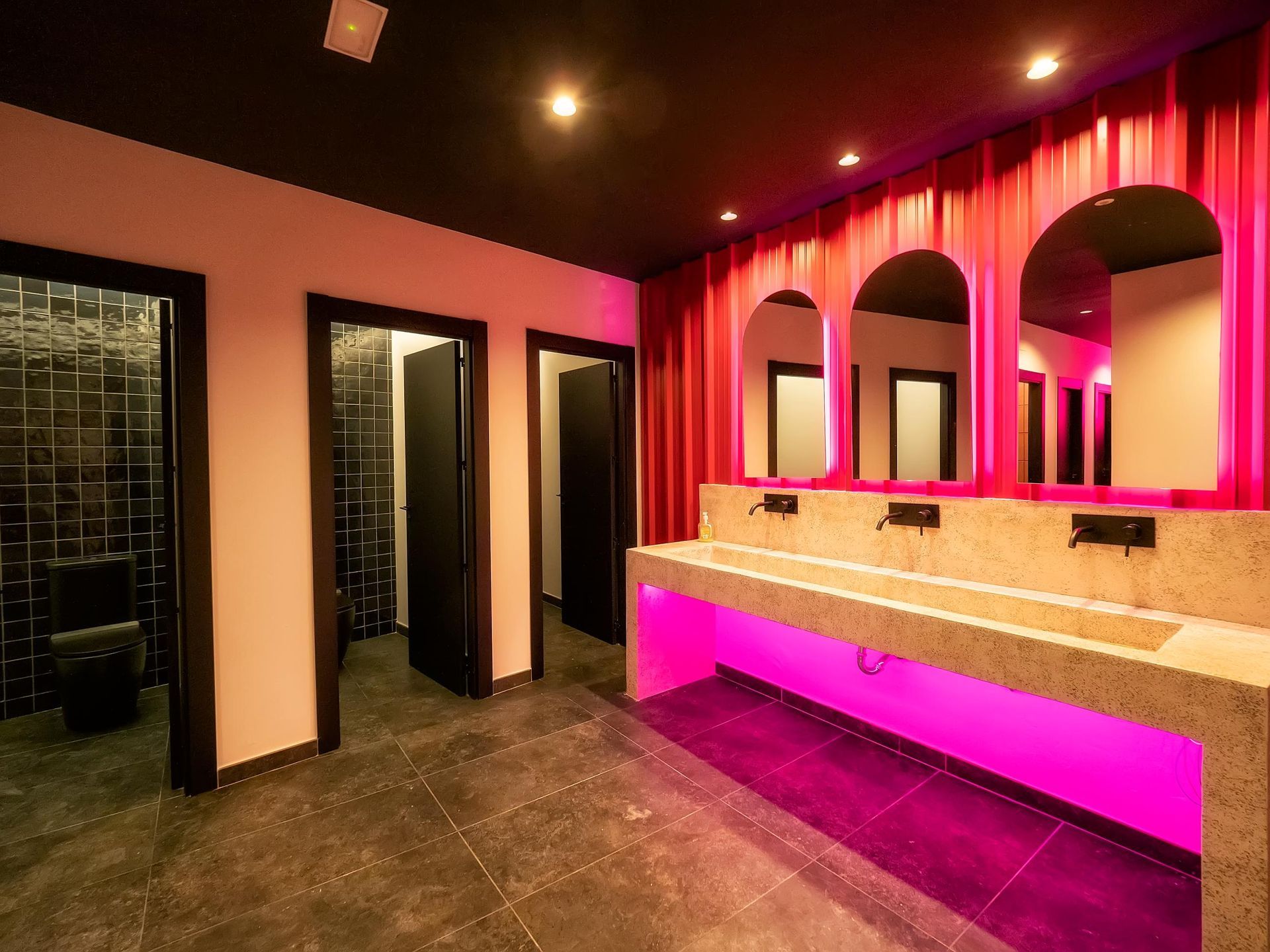 A bathroom with pink lights on the walls and a sink.