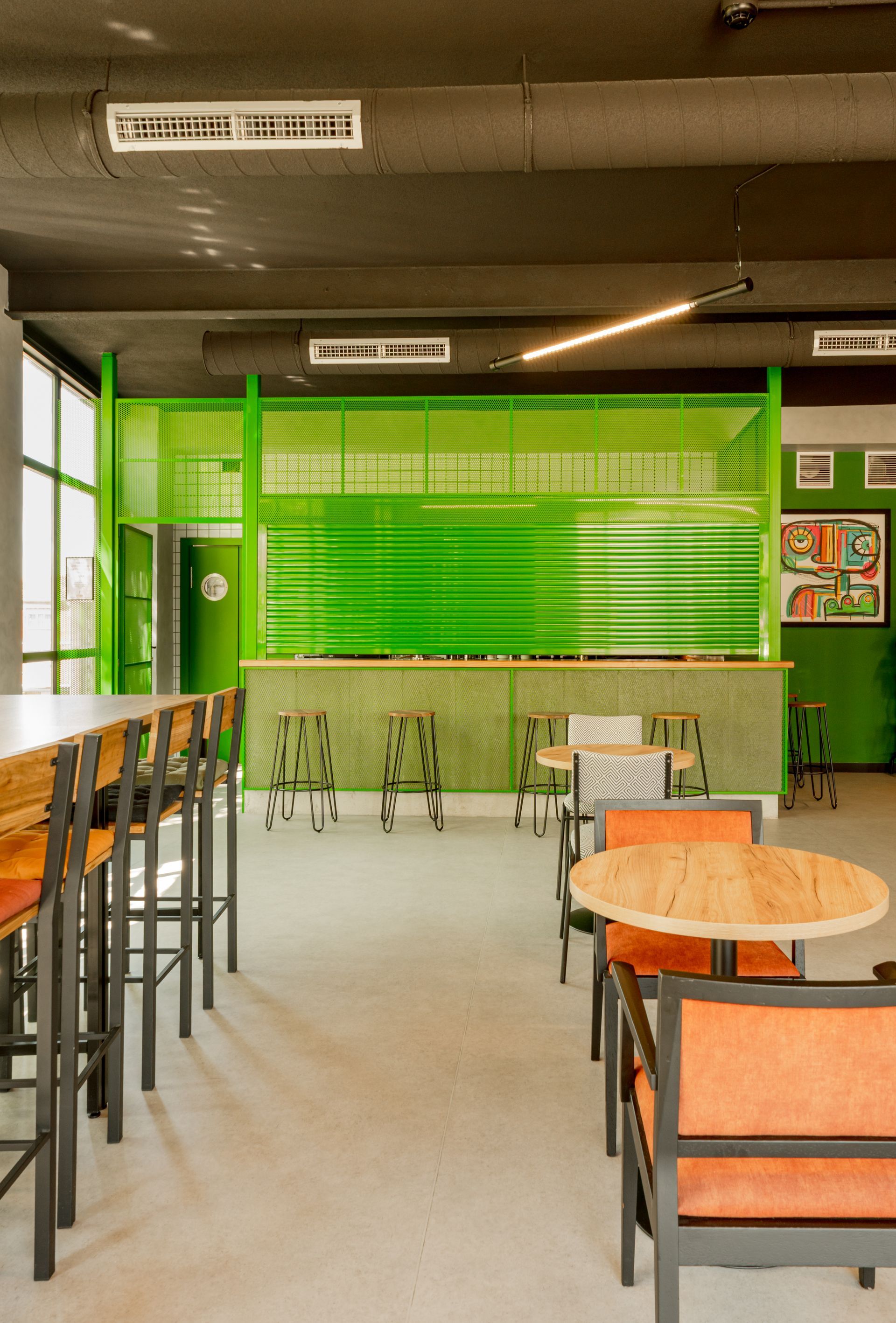 A coffee bar with tables and chairs and a green wall.