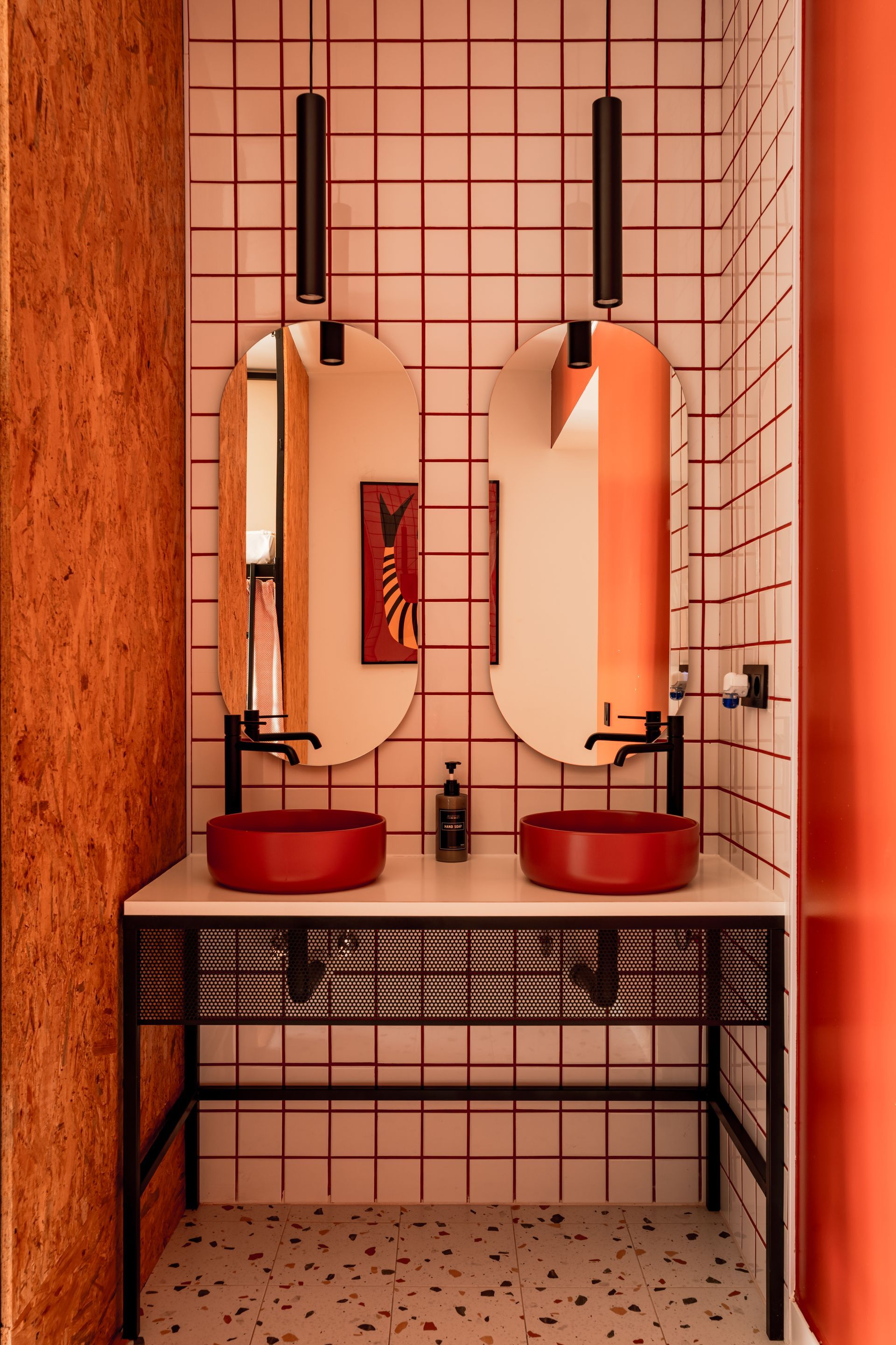 A bathroom with two red sinks and two mirrors.