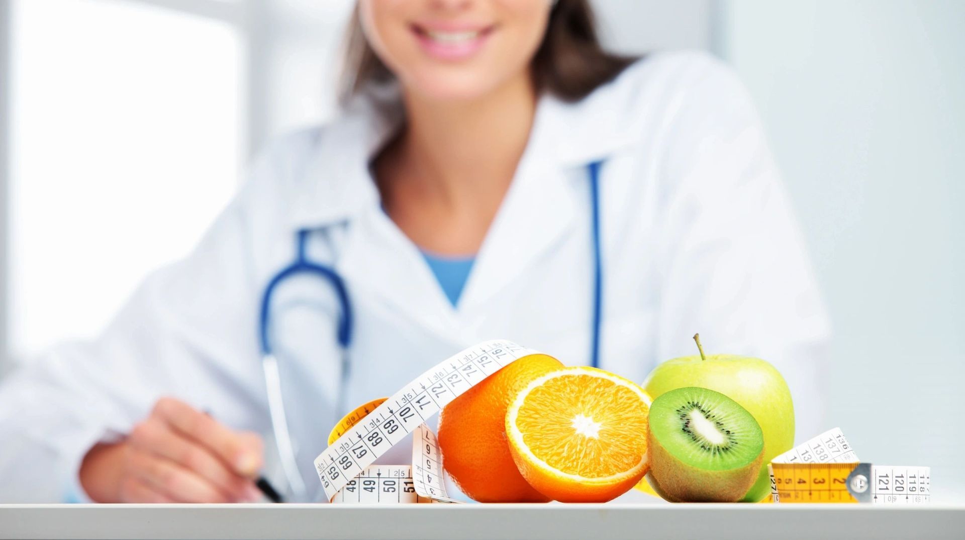 Nutrition consultation with doctor, tape measure, and sliced orange and kiwi on a table