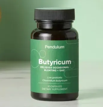 Green bottle of Pendulum Butyricum probiotic supplement with black cap on a pale green background