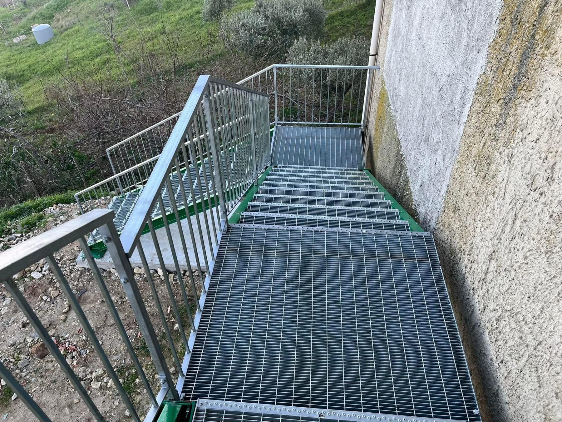 Scala esterna con griglia metallica e ringhiera che scende lungo un edificio.