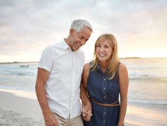 A man and a woman are holding hands on the beach  – Extractions in Lebanon, MO
